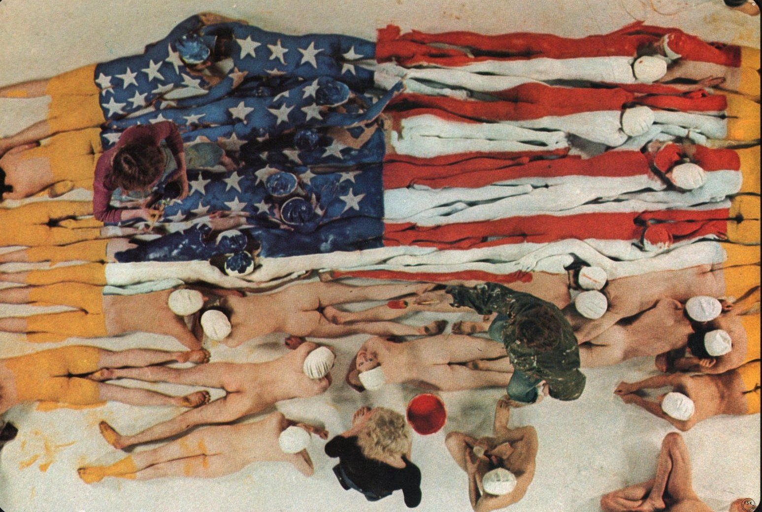 Menschen liegen unter einer Flagge, die der US-Flagge ähnelt. Gelbe und rote Streifen sind zu sehen.