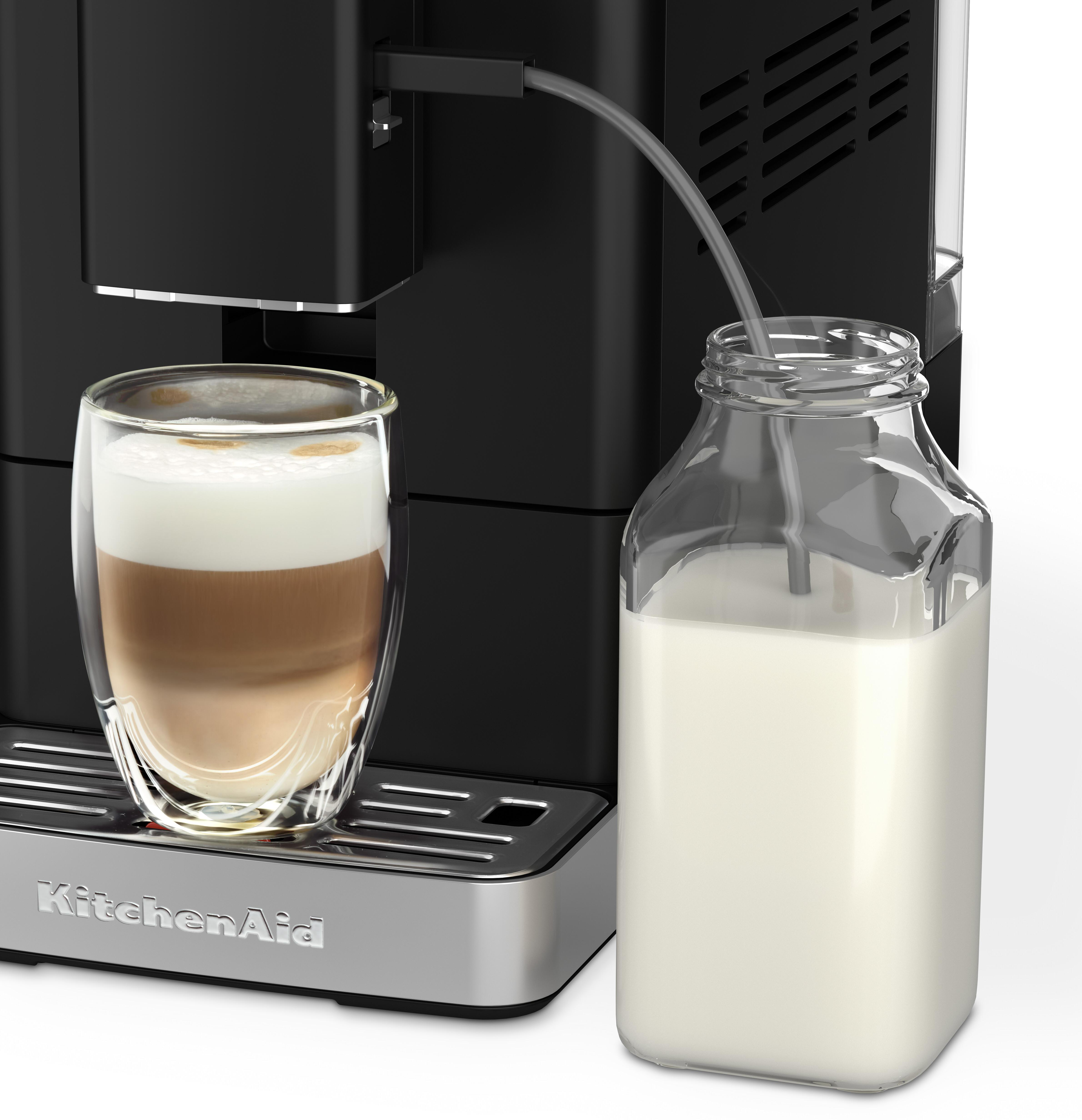 Eine Kaffeemaschine mit Milchkaraffe und Glas Latte Macchiato.