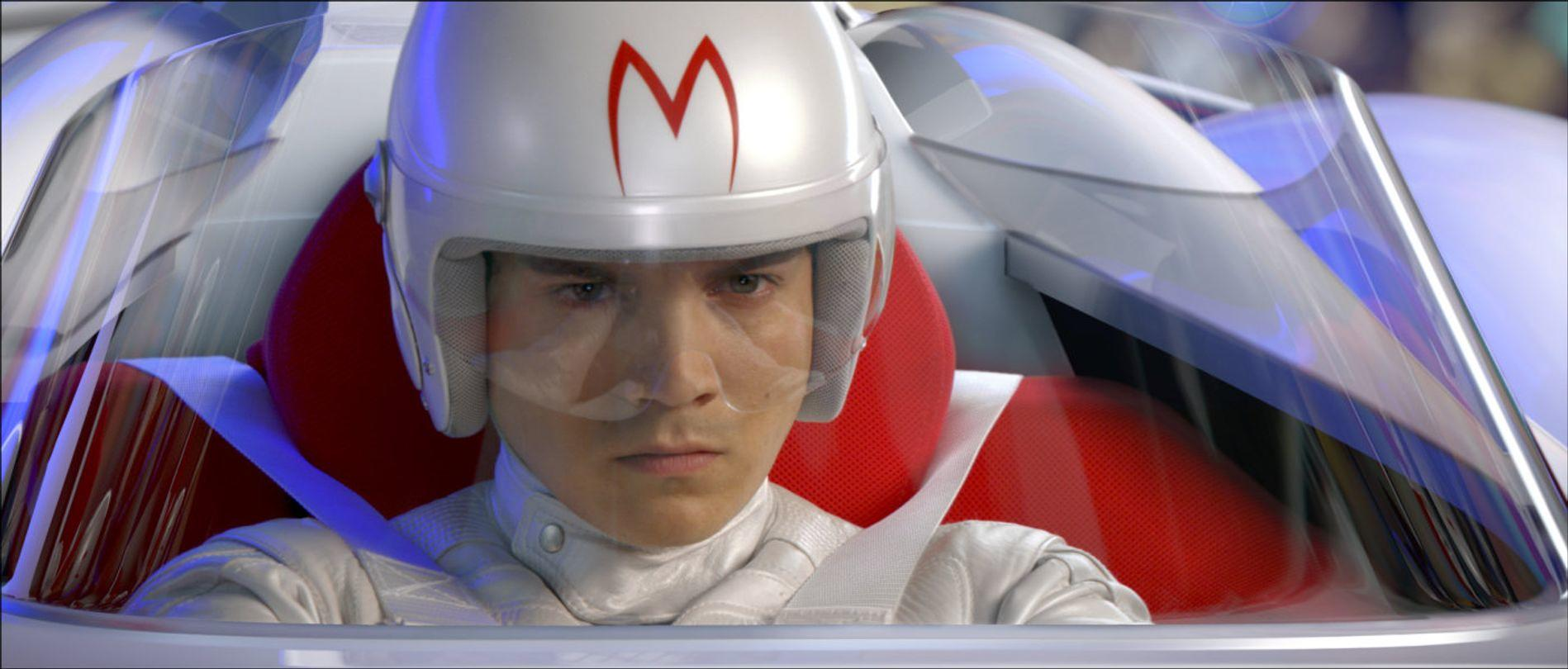 Ein Mann in einem weißen Rennanzug und Helm fährt in einem Auto mit roten Sitzen.