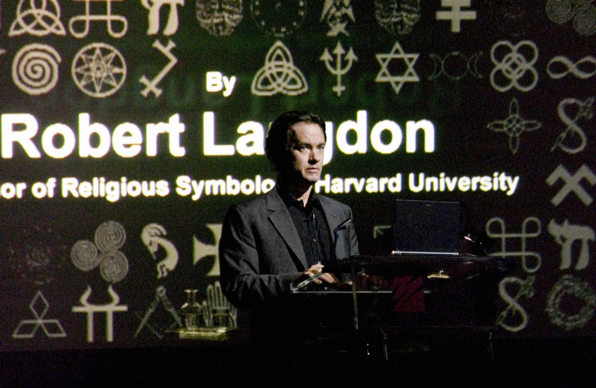 Mann vor Projektion mit Symbolen und Text, der Robert Langdon und Harvard University erwähnt.
