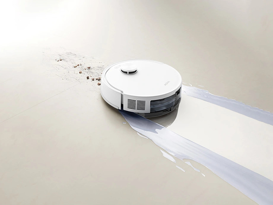 Biały robot sprzątający czyści brudną i mokrą powierzchnię podłogi.