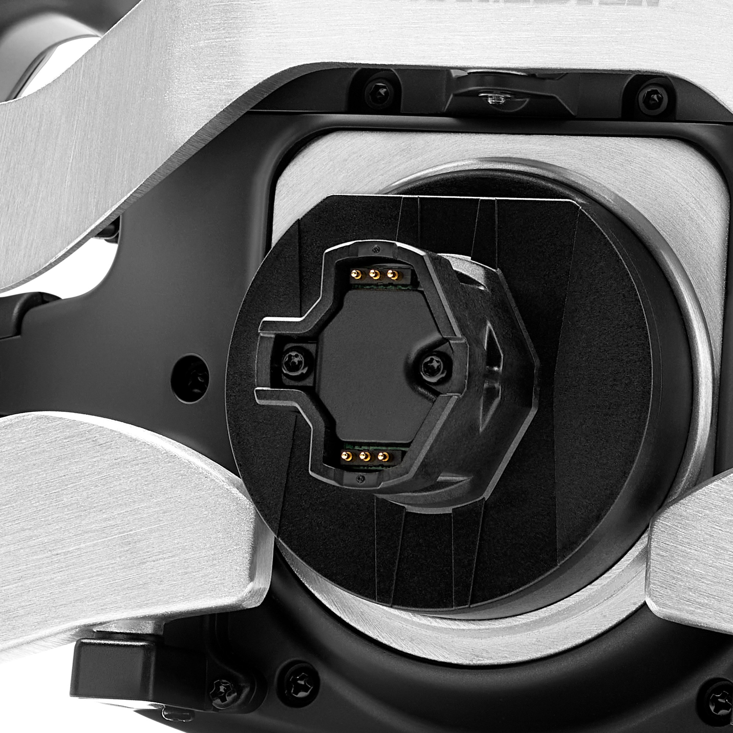 Close-up van een zwarte hexagonale connector met gouden pinnen, omgeven door geborsteld metaal.