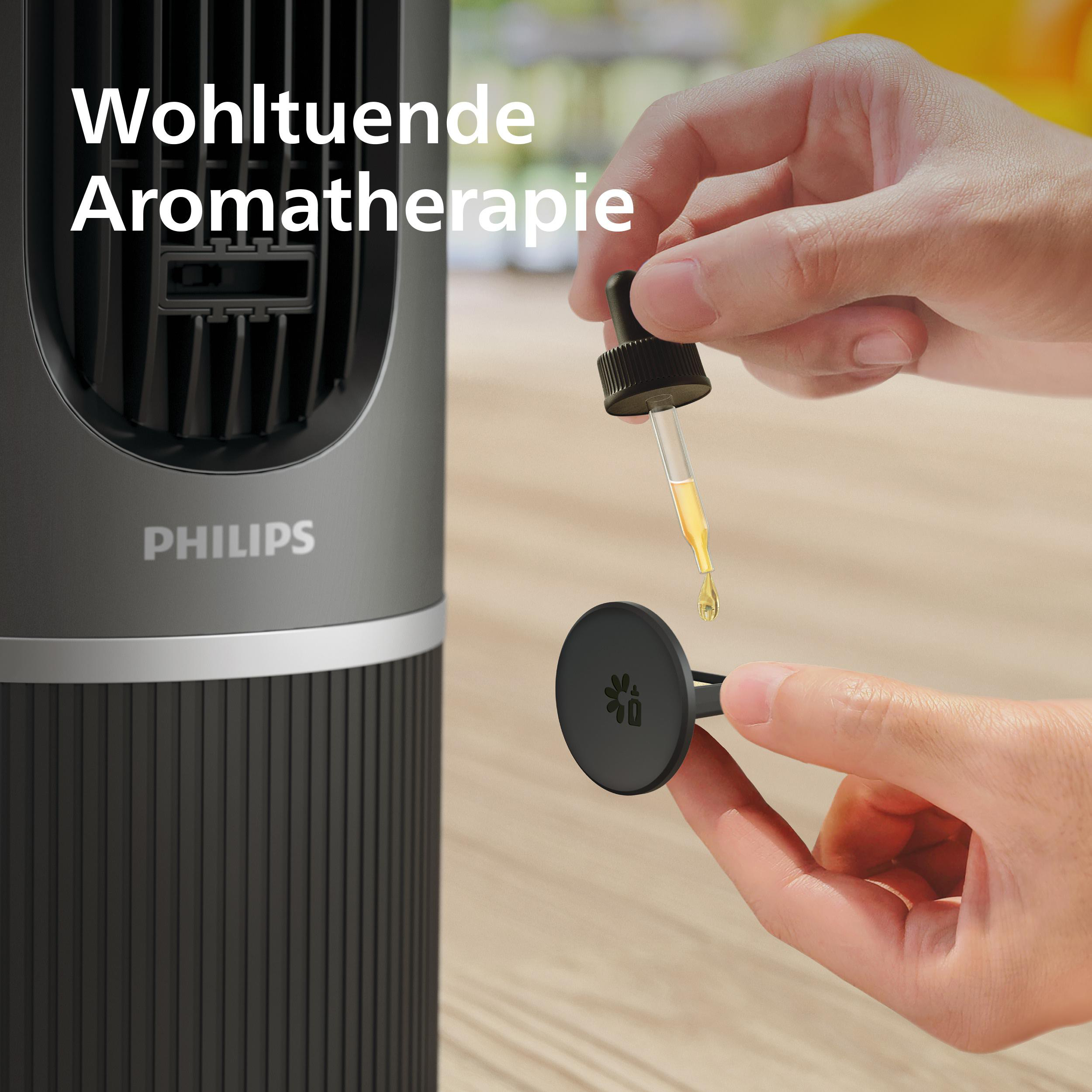Eine Hand tropft Öl auf einen Diffusor neben einem Philips Luftreiniger.