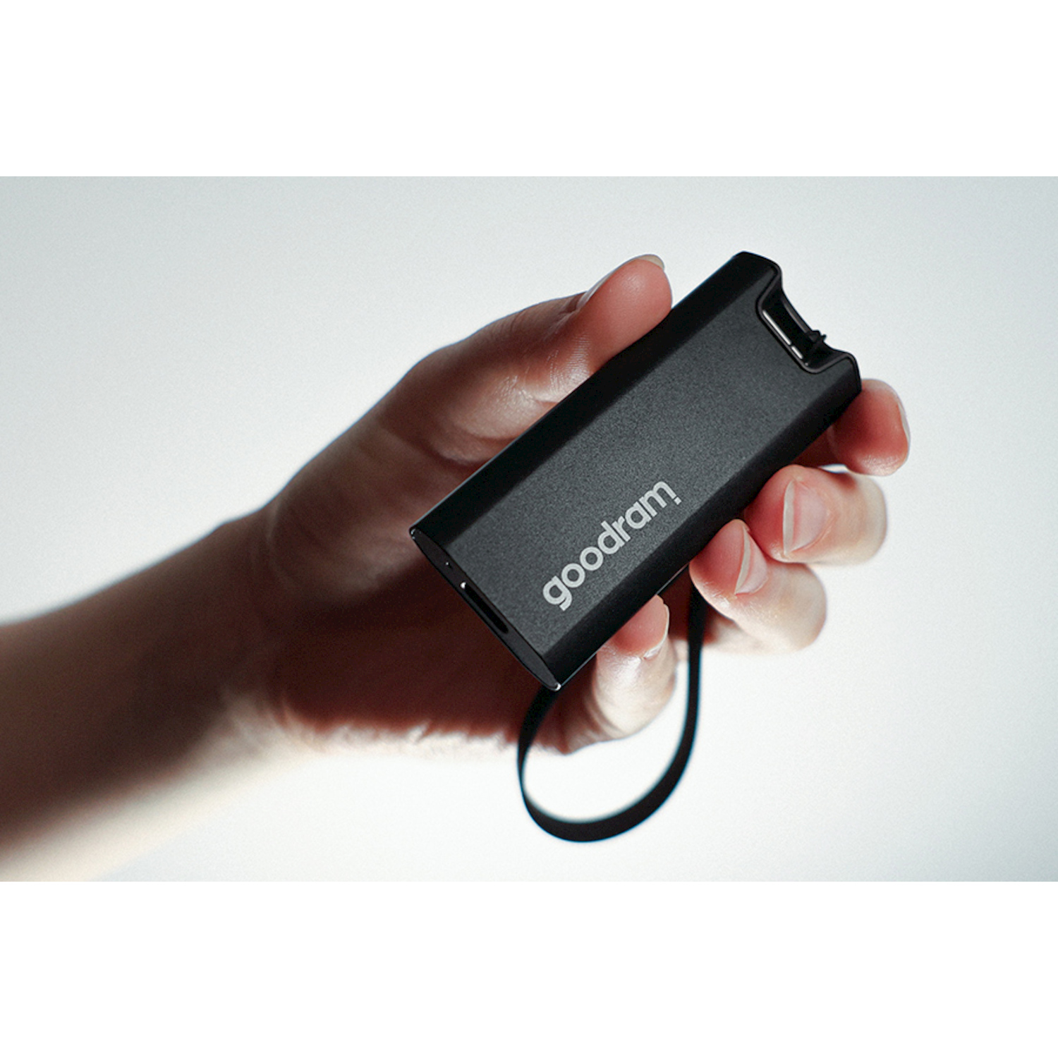 Una mano tiene una chiavetta USB nera con il marchio 'goodram'.
