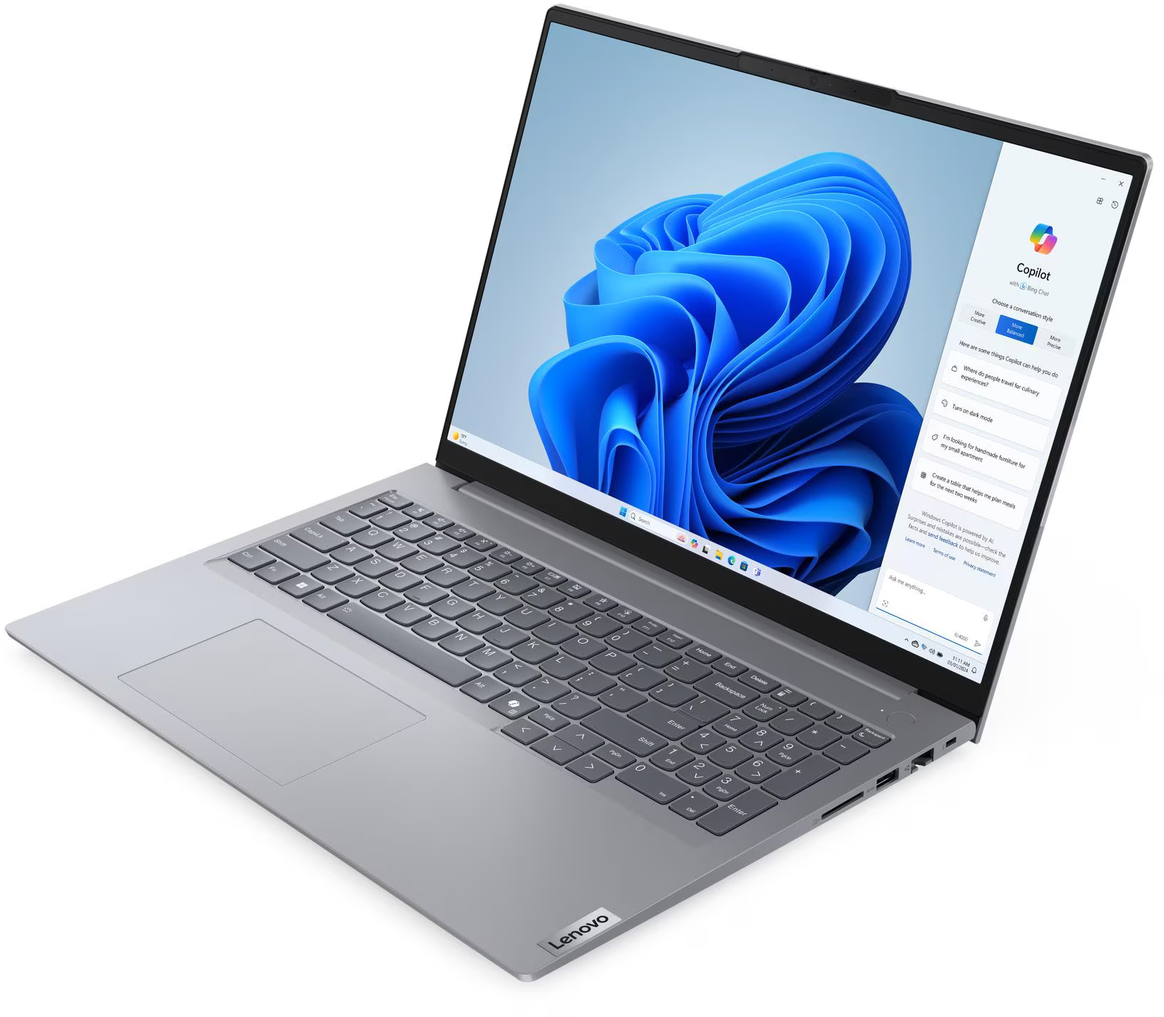 Egy ezüst laptop kék Windows háttérrel és Copilot ablak.