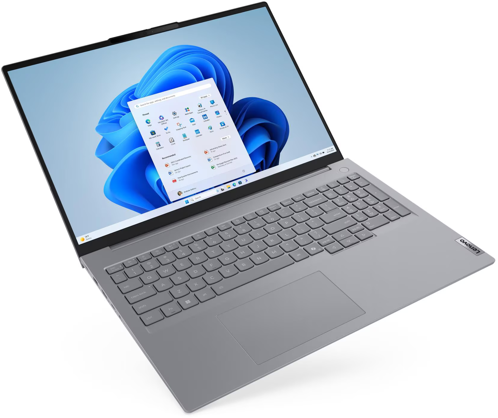 Egy szürke Lenovo laptop nyitva van, a Windows 11 indítómenüje látható a képernyőn.
