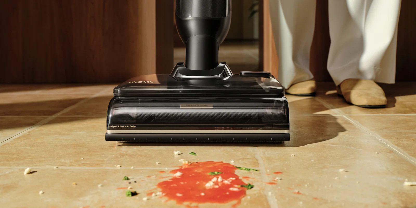 Czarny odkurzacz czyści czerwony rozlew na beżowej podłodze.