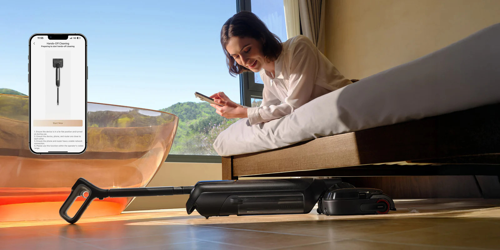 Kobieta na łóżku używa telefonu, pod spodem znajduje się odkurzacz.