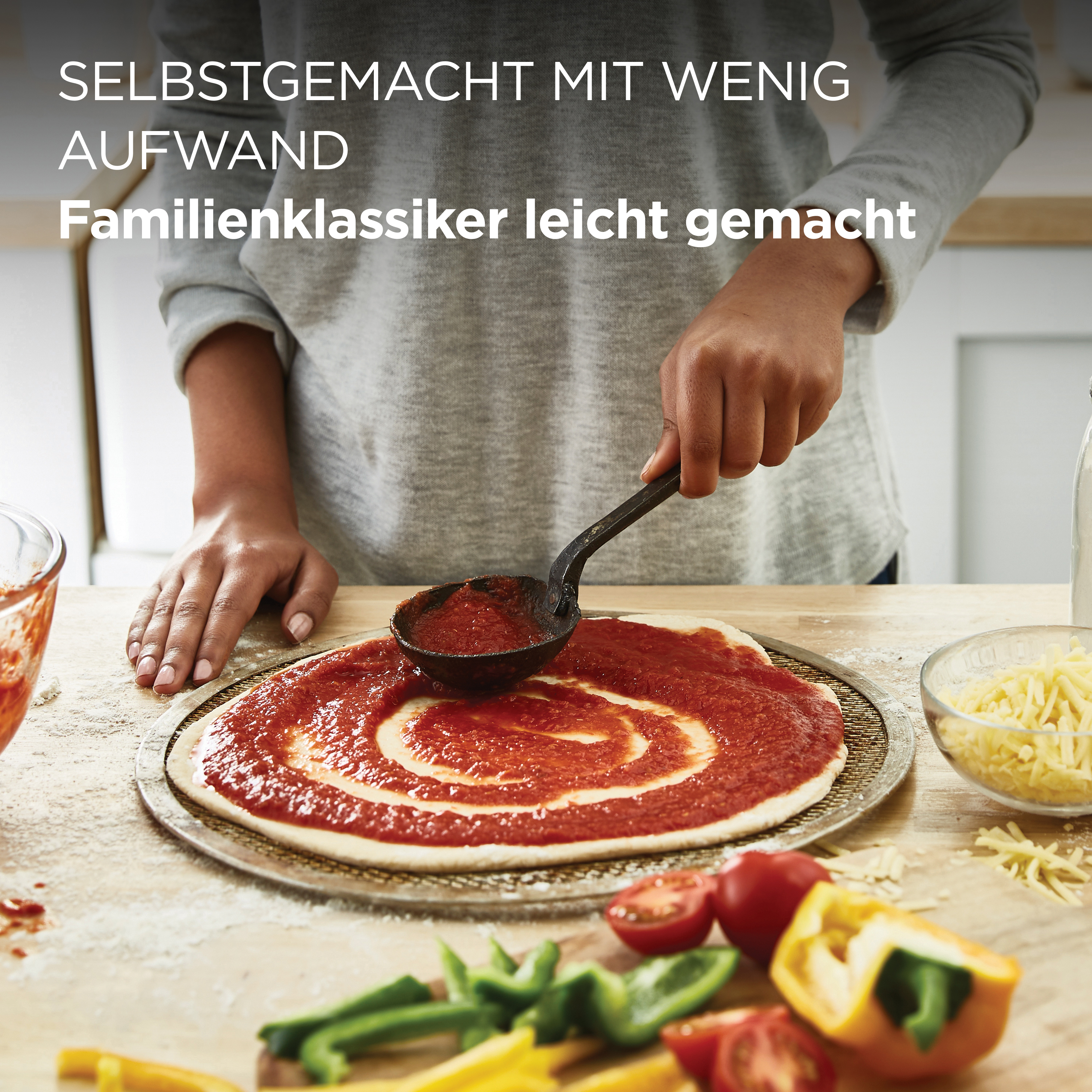 Eine Person verteilt Tomatensoße mit einer Schöpfkelle auf einem Pizzaboden.