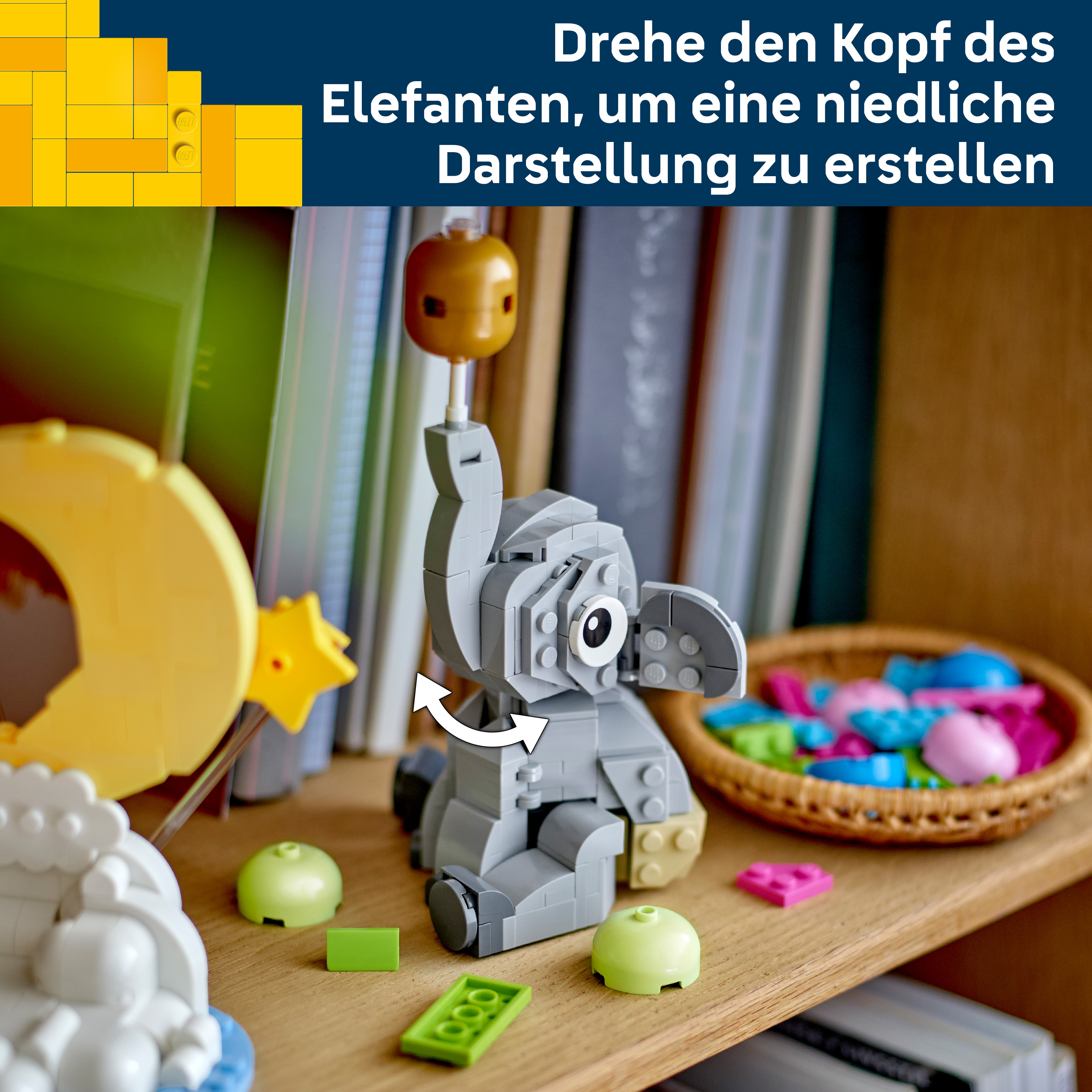 Grauer Lego-Elefant mit gelbem Ball auf dem Kopf, drehbar, auf einem Regal.