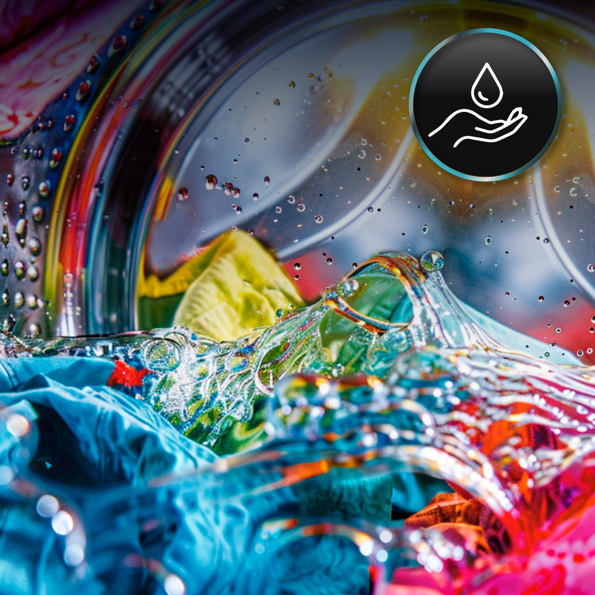 Ropa colorida en una lavadora con agua y salpicaduras. Icono de mano con gota arriba a la derecha.