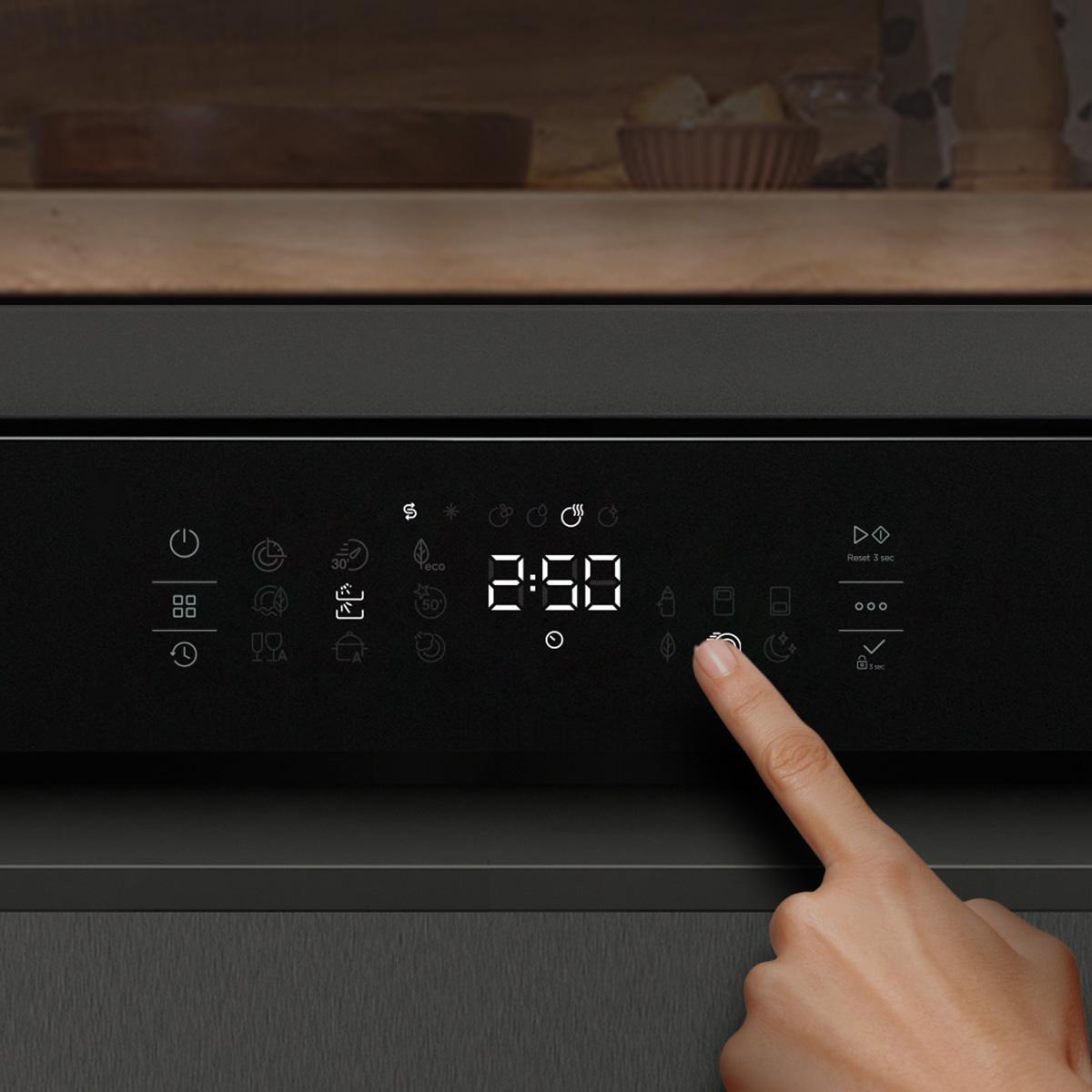 Un dedo presiona el botón en el panel de control de un lavavajillas moderno con pantalla digital.