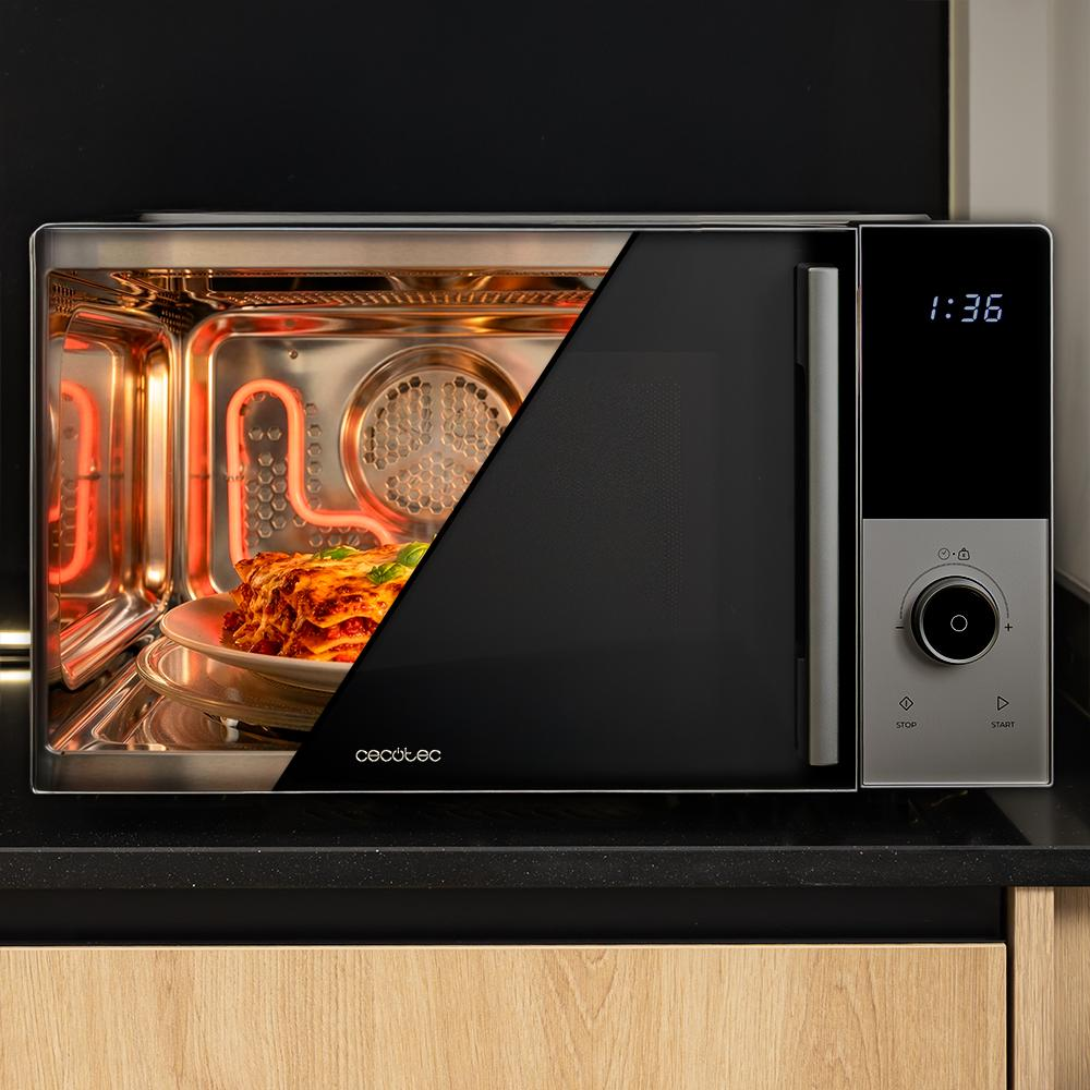 Un plato de lasaña se cocina dentro de un microondas iluminado con panel.