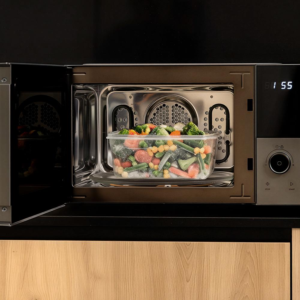 Un recipiente transparente con verduras mixtas congeladas en un microondas.