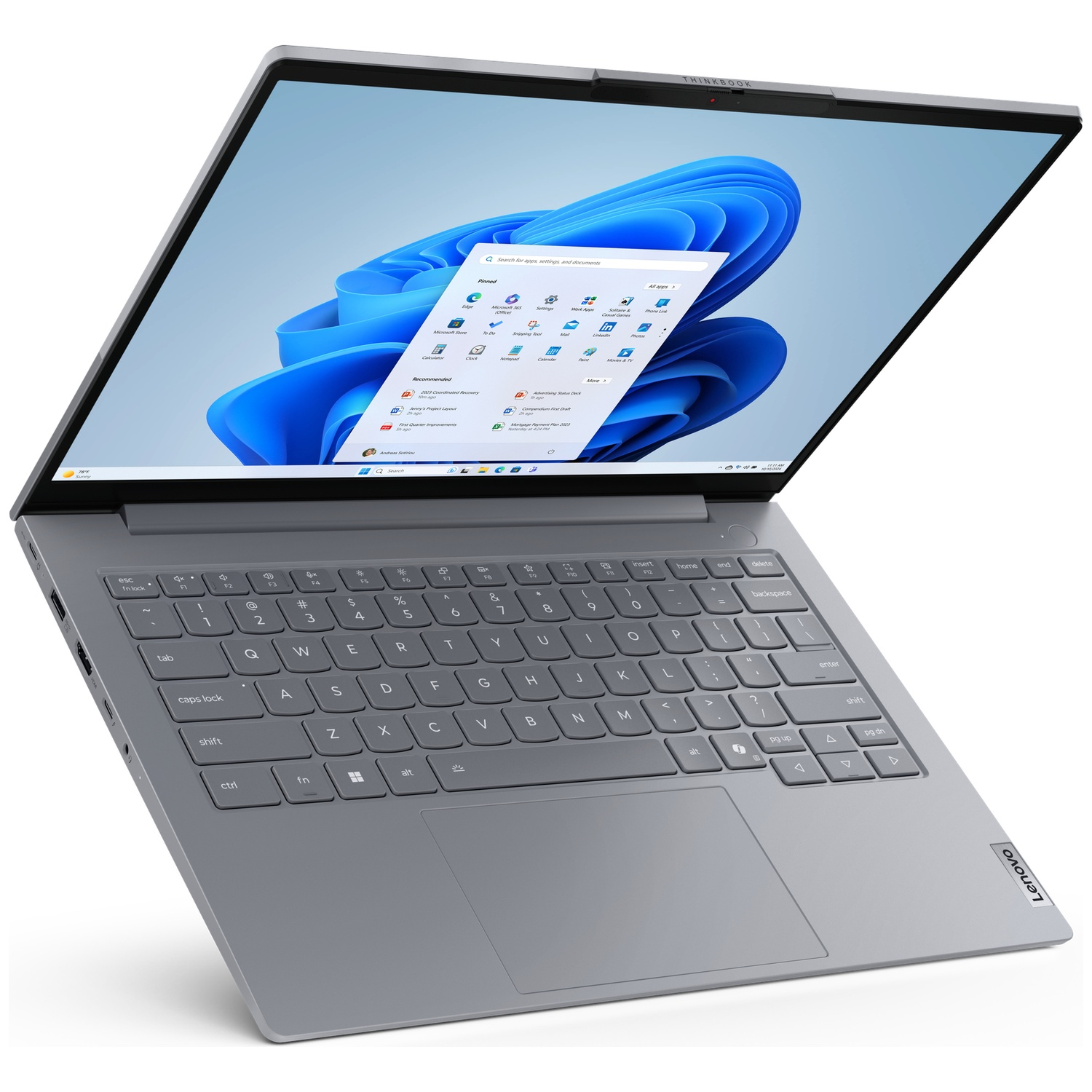 A silver Lenovo ThinkBook laptop is open, displaying Windows 11 on its screen and keyboard.