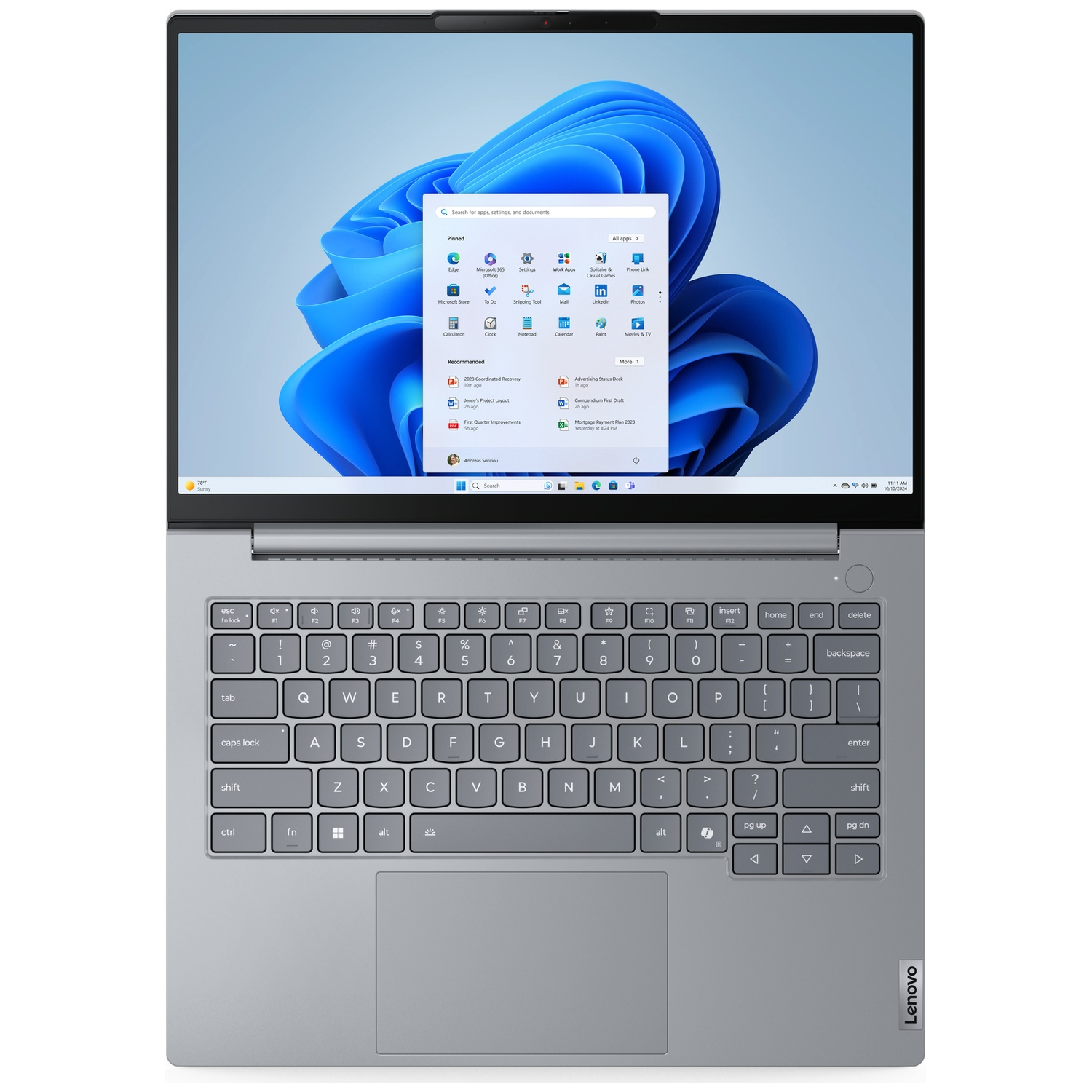 A silver Lenovo laptop is open, showing the Windows 11 start menu on its screen.