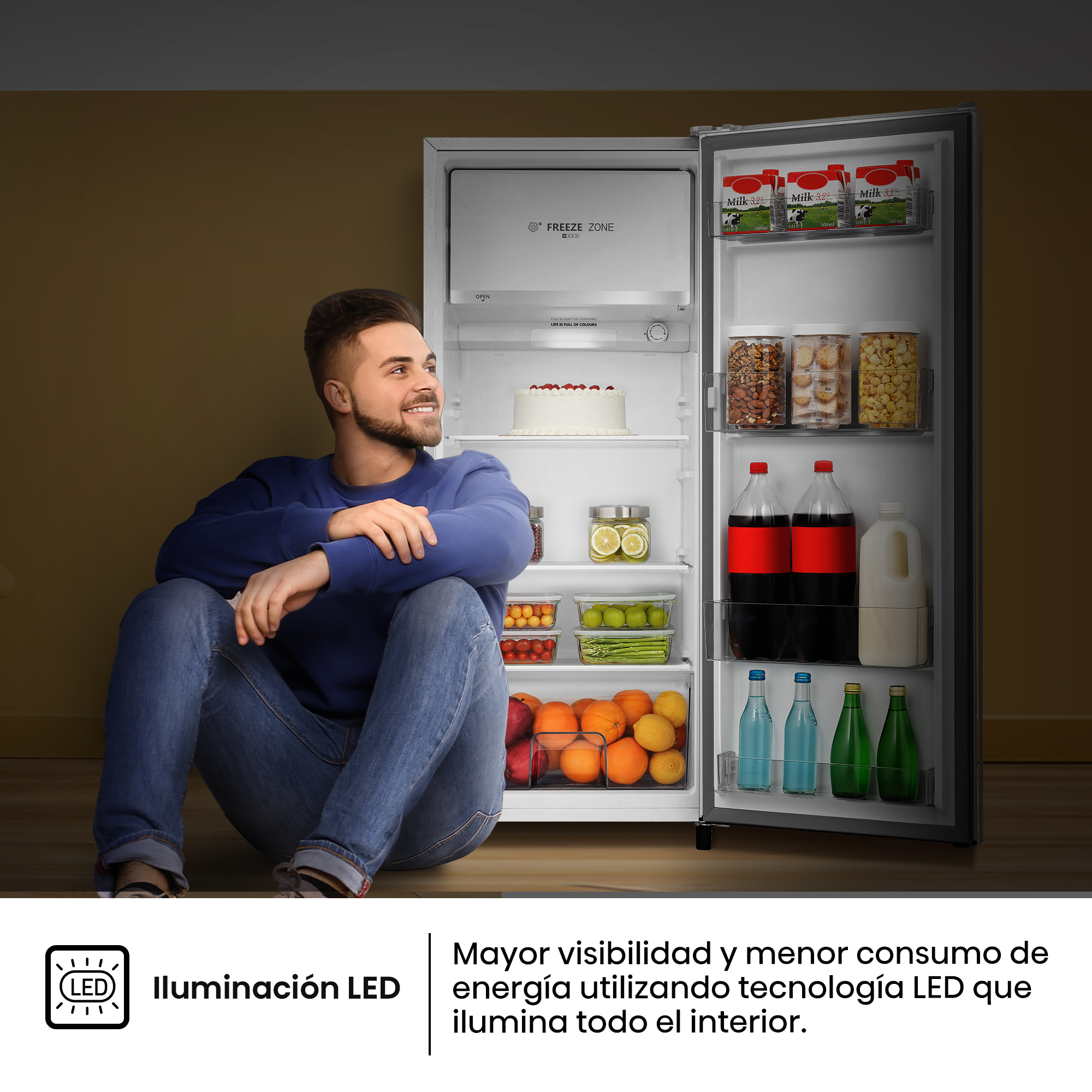 Un hombre se sienta frente a un refrigerador abierto lleno de comida y bebidas.