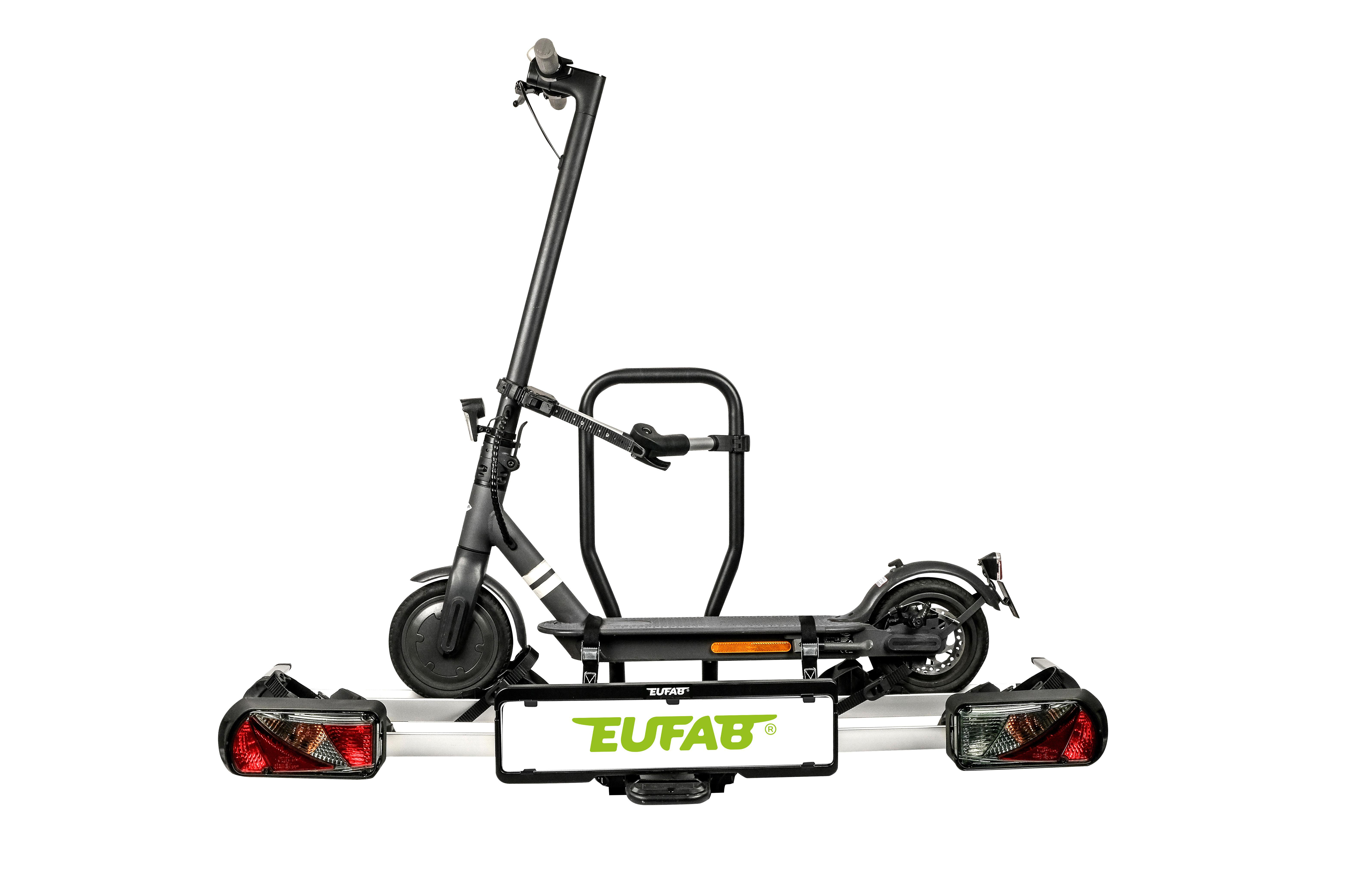 Ein schwarzer E-Scooter ist auf einem Anhänger montiert, mit Nummernschild und Rückleuchten.