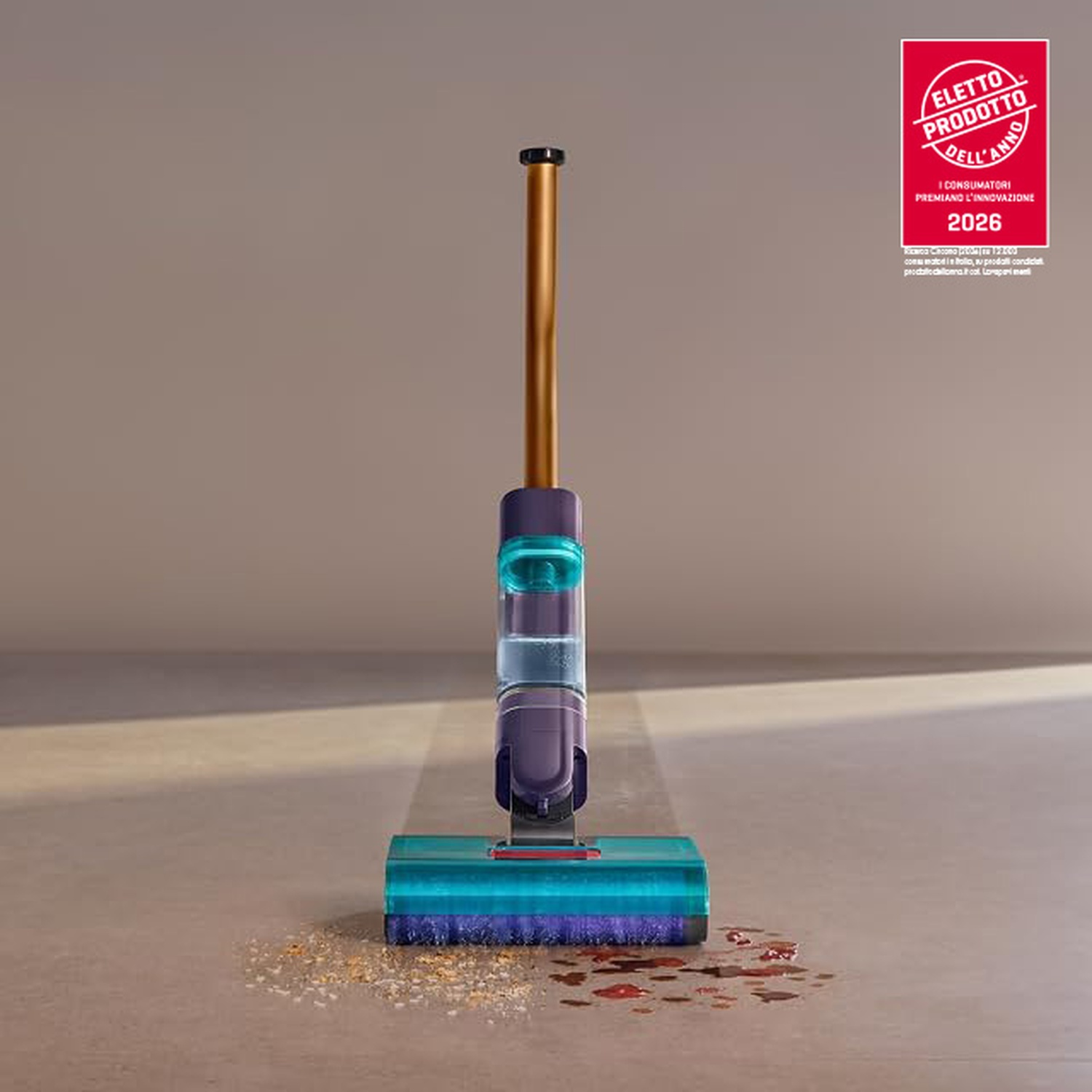 Un aspirapolvere viola e oro pulisce un pavimento con sporco e liquido.