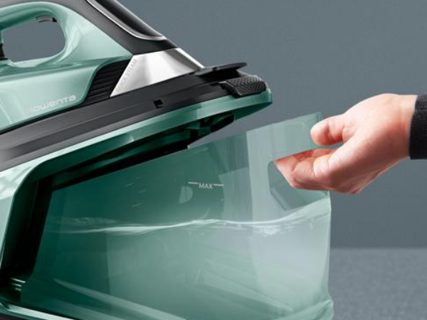 La mano extrae un depósito de agua transparente de una plancha.