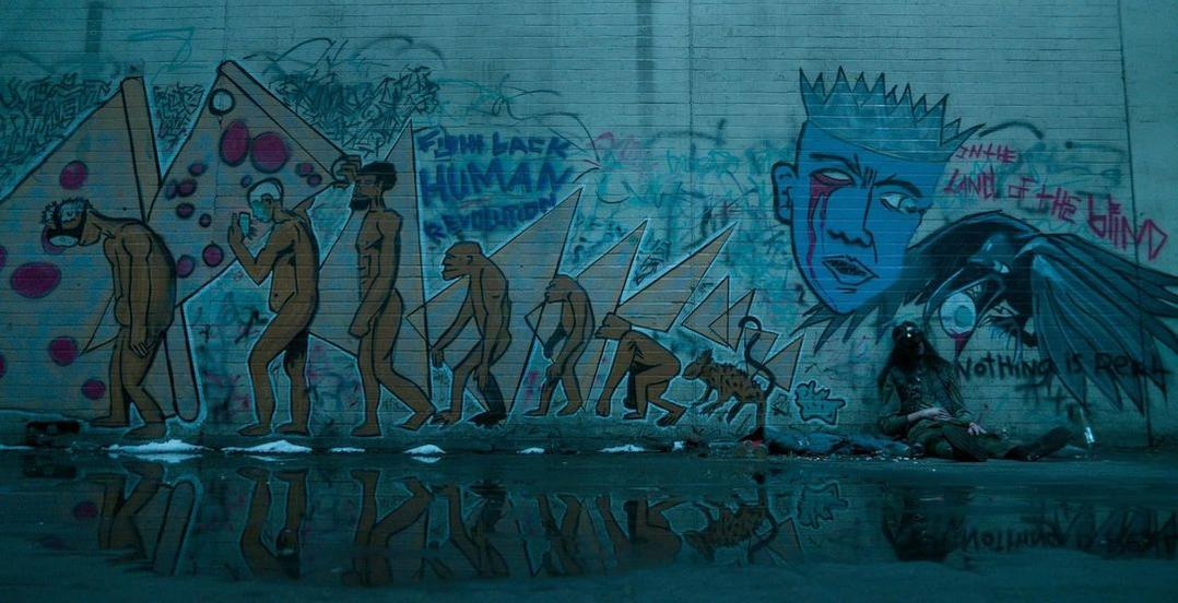 Graffiti zeigt Evolution, ein Gesicht, einen Raben und eine sitzende Person.