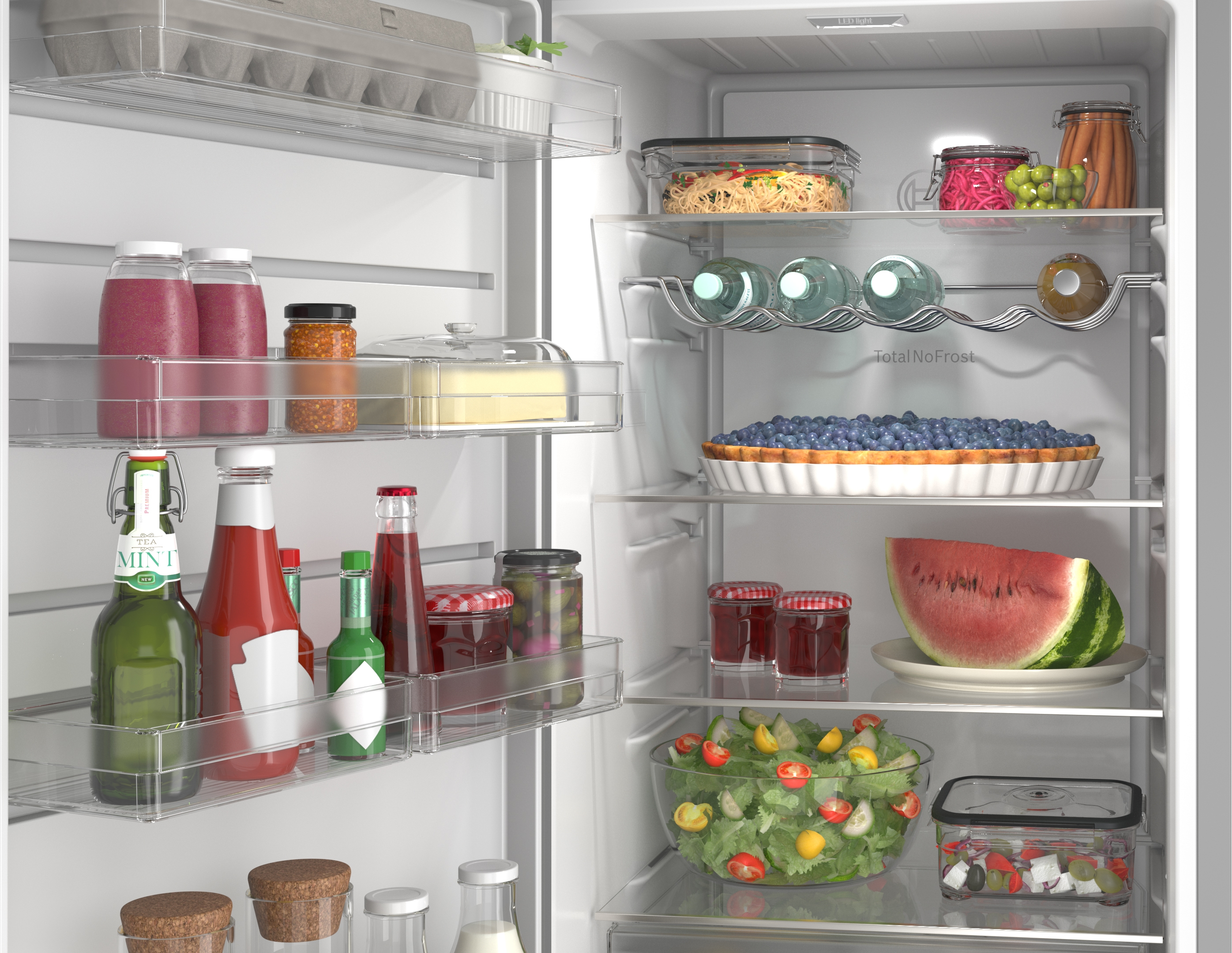 A refrigerator stocked with food including fruit, vegetables, a pie, and drinks.