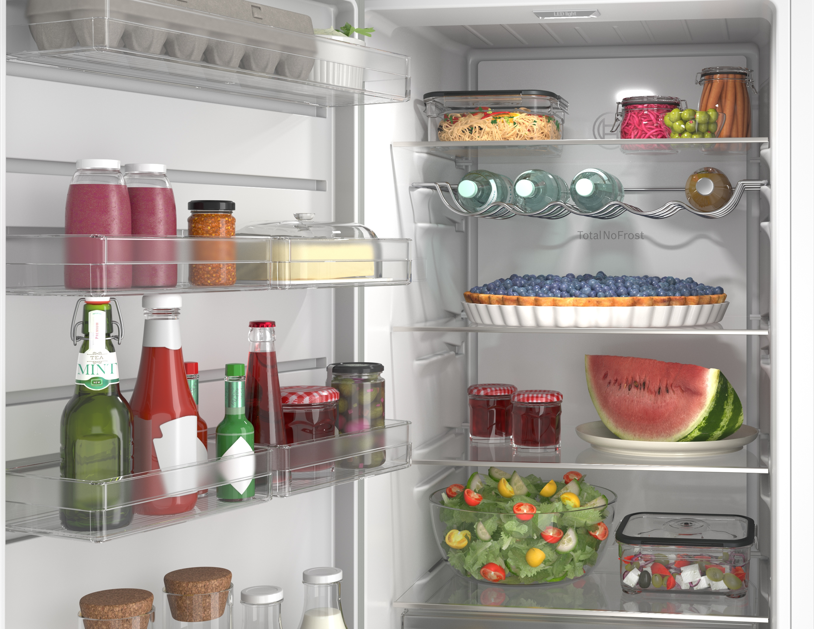 An open refrigerator filled with food: berry pie, watermelon, salad, and bottles.