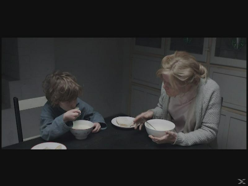 Ein Junge und eine Frau sitzen an einem Tisch und essen.