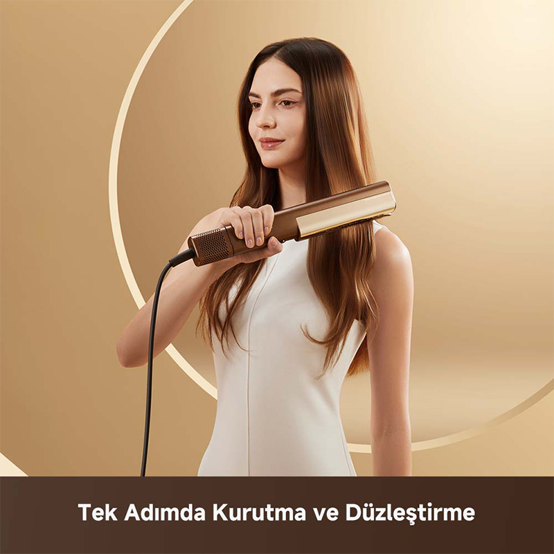 Kadın, bej arka plana karşı altın rengi saç düzleştiriciyle kahverengi saçını düzleştiriyor.