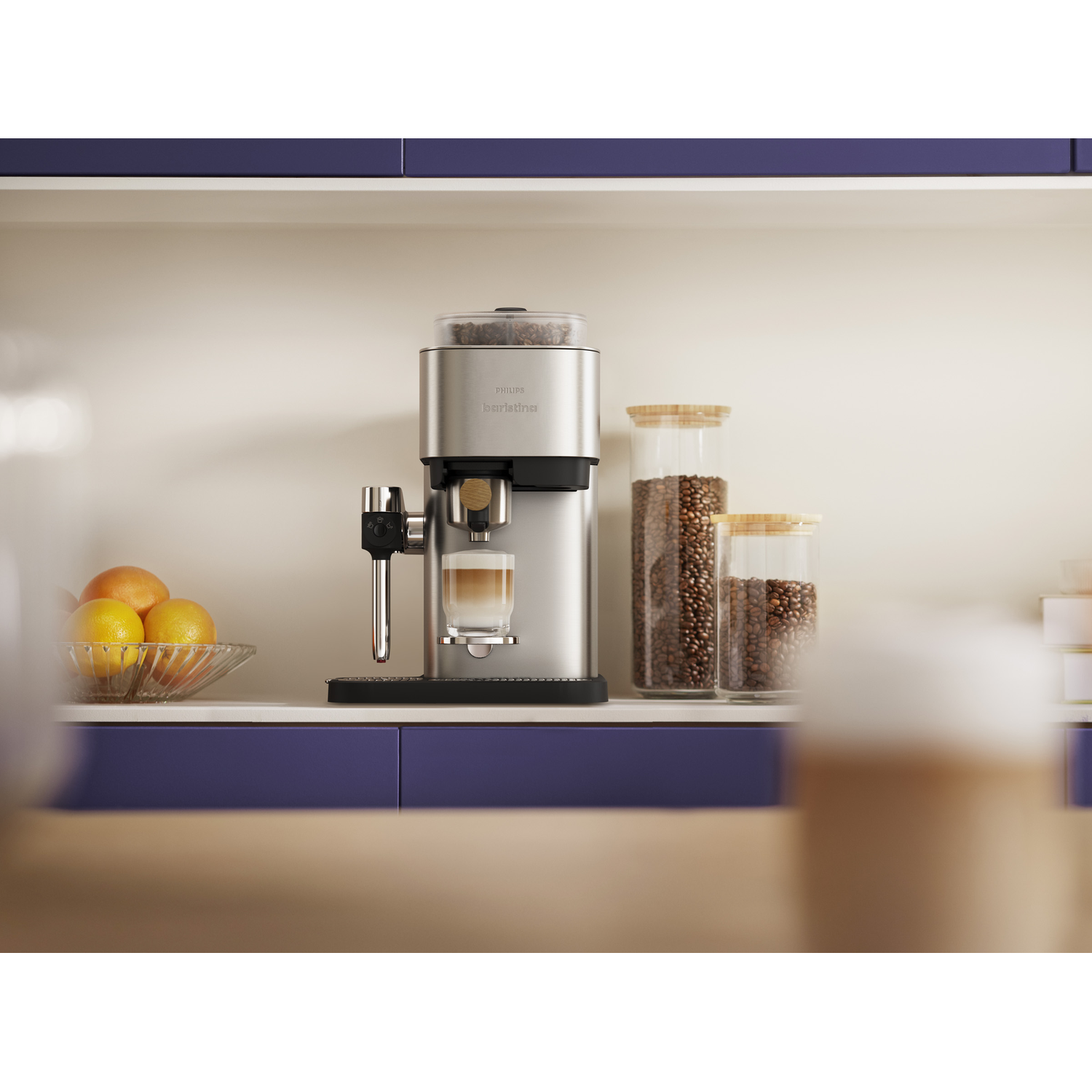Een zilveren koffiezetapparaat zet een latte, met sinaasappels in een kom en potten koffiebonen.