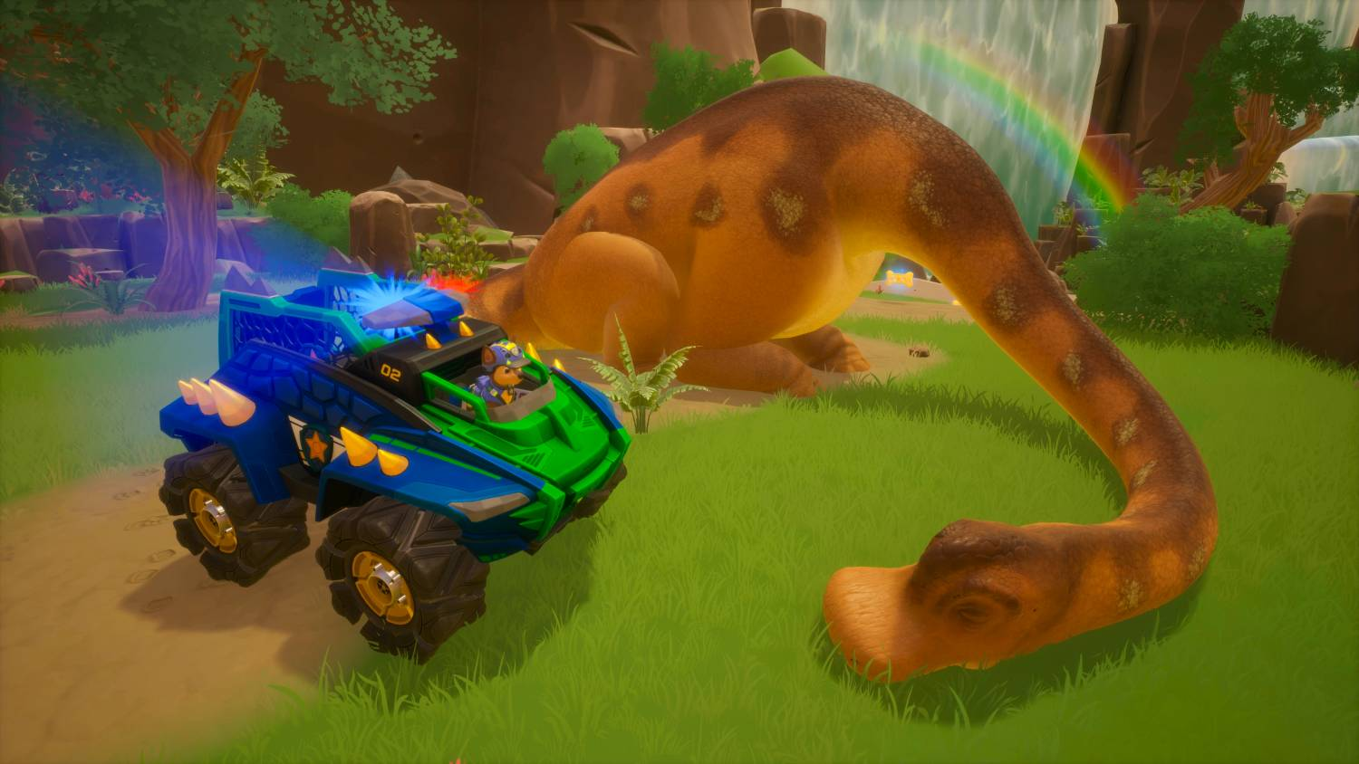 Un camión monstruo azul y verde conduce por un camino cubierto de hierba junto a un dinosaurio.