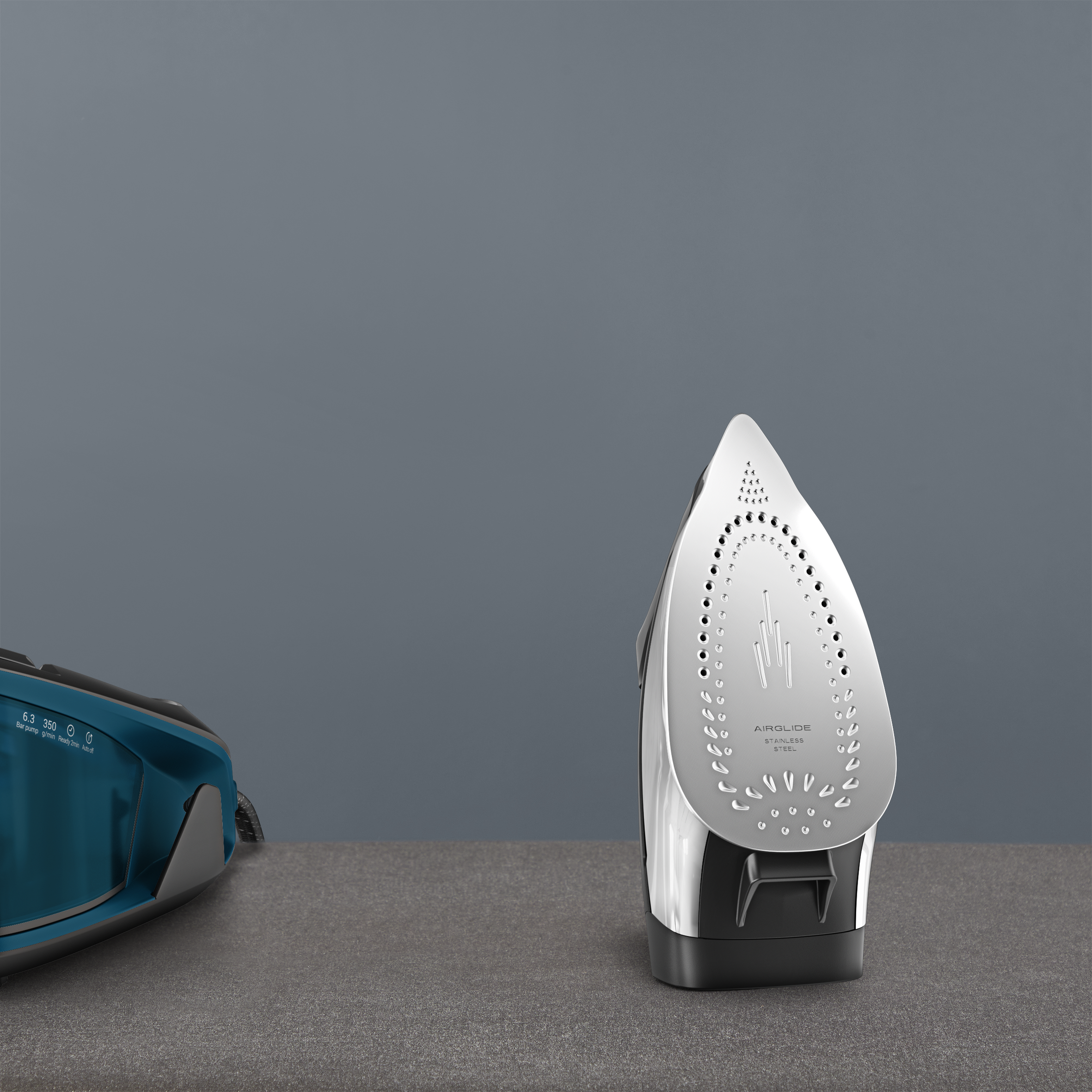 Una plancha de vapor azul y una plancha plateada sobre una superficie gris.