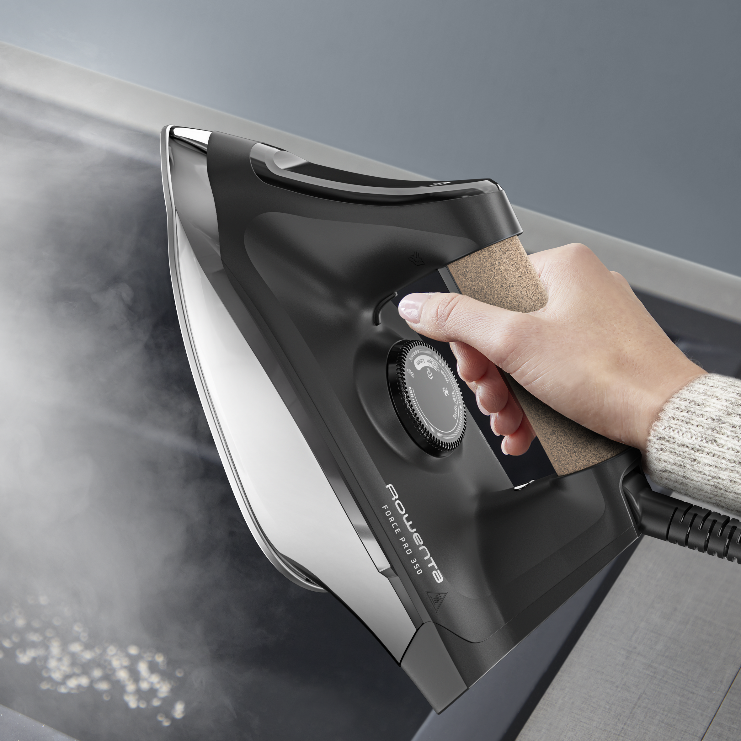 Una mano sujetando una plancha negra, con vapor saliendo.