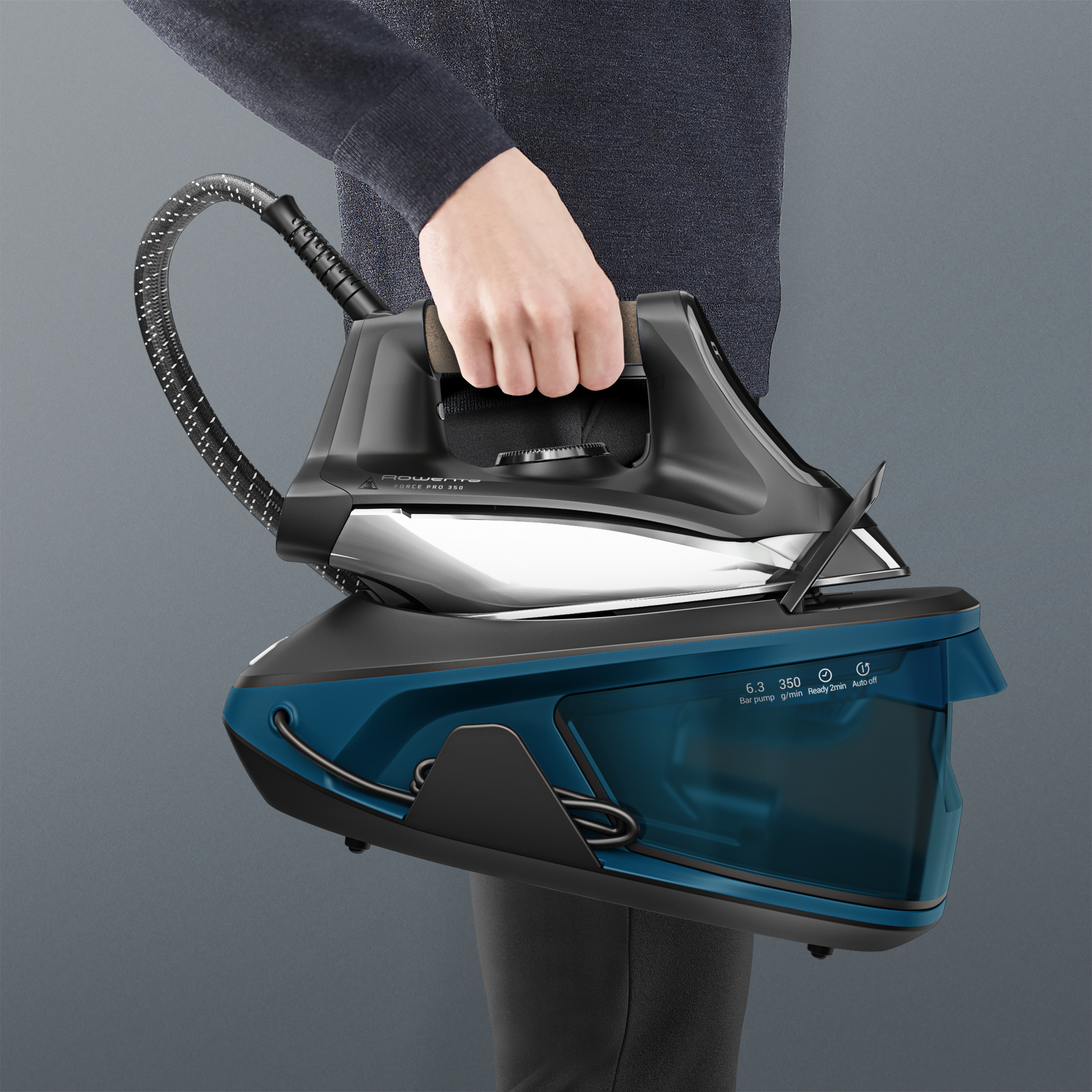 Persona sujetando una unidad de plancha de vapor con depósito de agua azul y plancha negra.