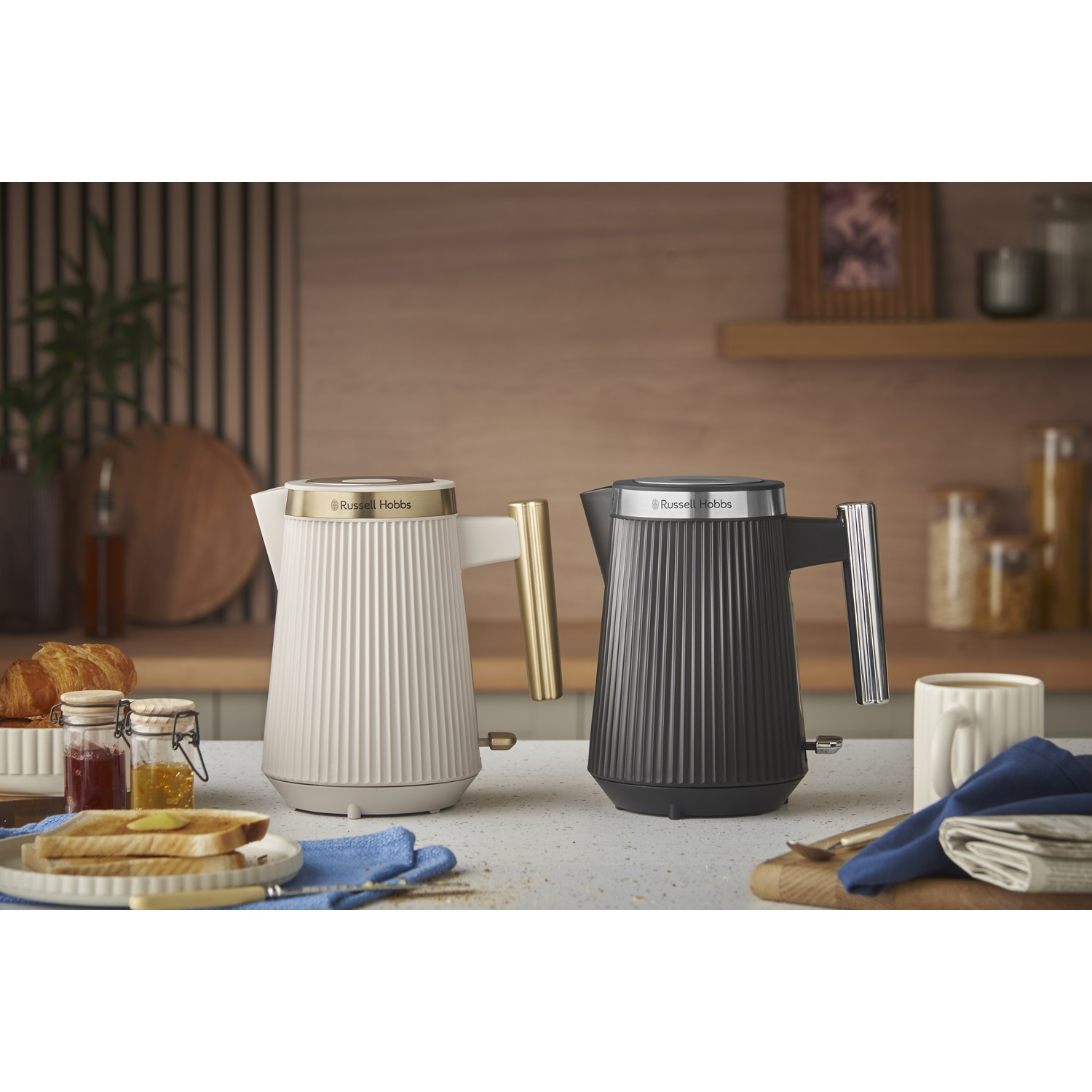 Twee Russell Hobbs waterkokers, één wit, één zwart, met ontbijt op de voorgrond.