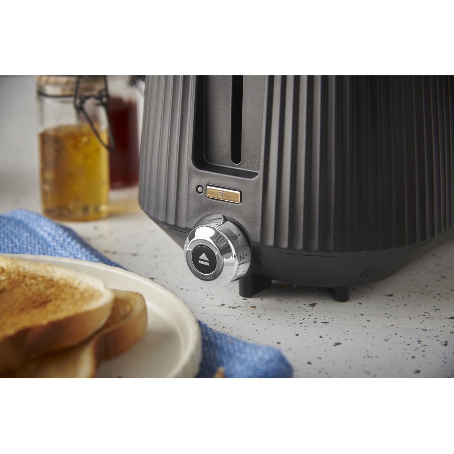 Un grille-pain noir avec des toasts sur une assiette à côté.