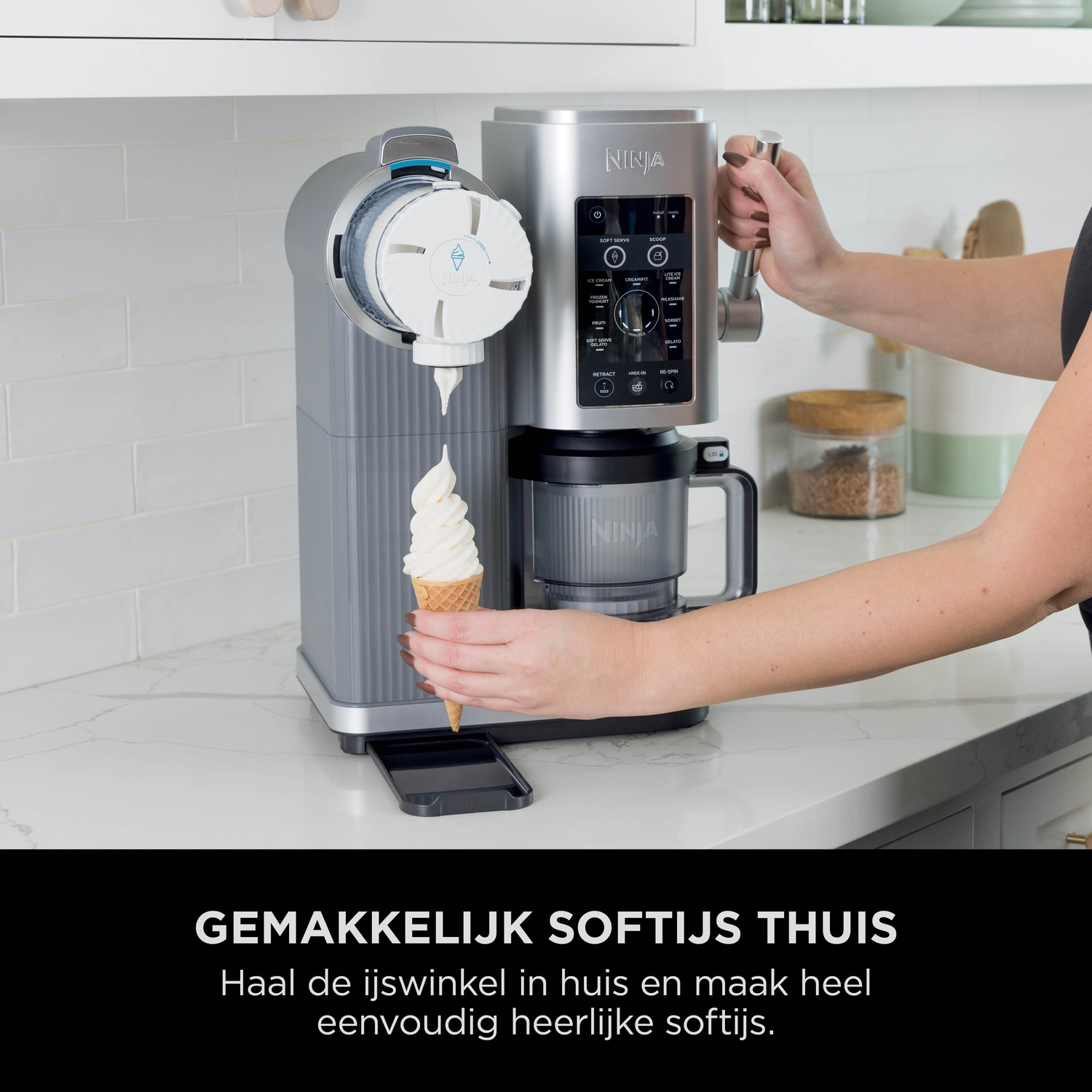 A Ninja soft serve machine dispenses ice cream into a cone. A hand turns the handle.