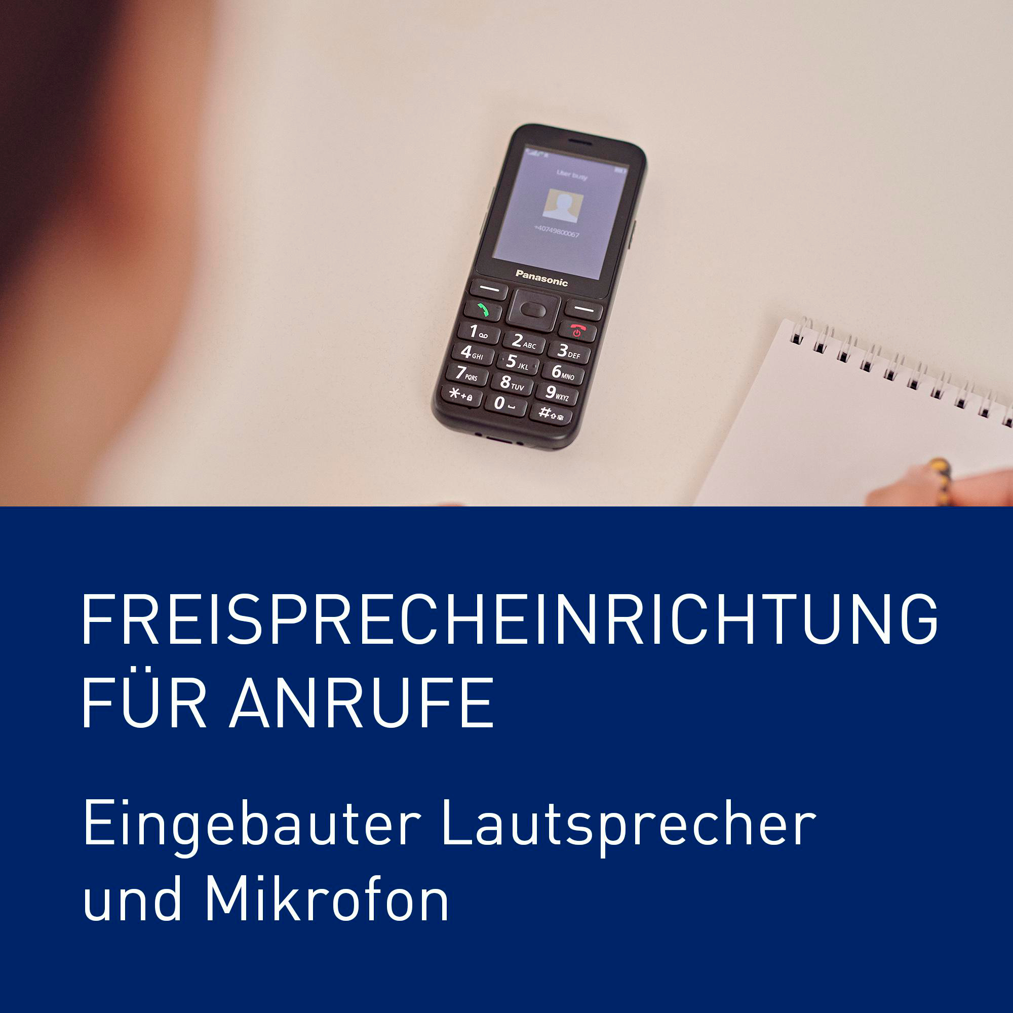 Ein Panasonic-Telefon mit Tasten und einem Bildschirm liegt neben einem Notizbuch.