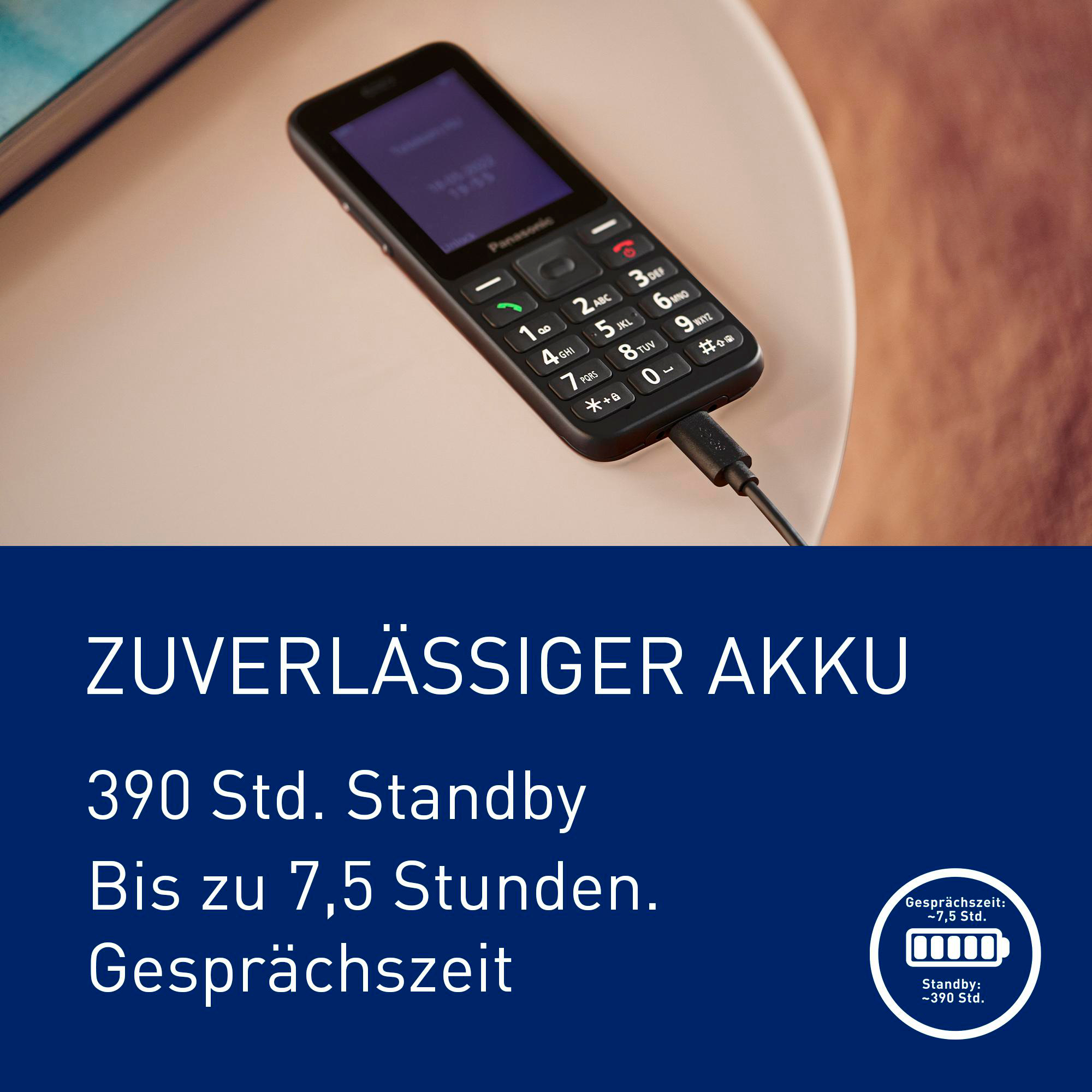 Ein schwarzes Panasonic-Handy mit Ladekabel, das auf einem Tisch liegt.