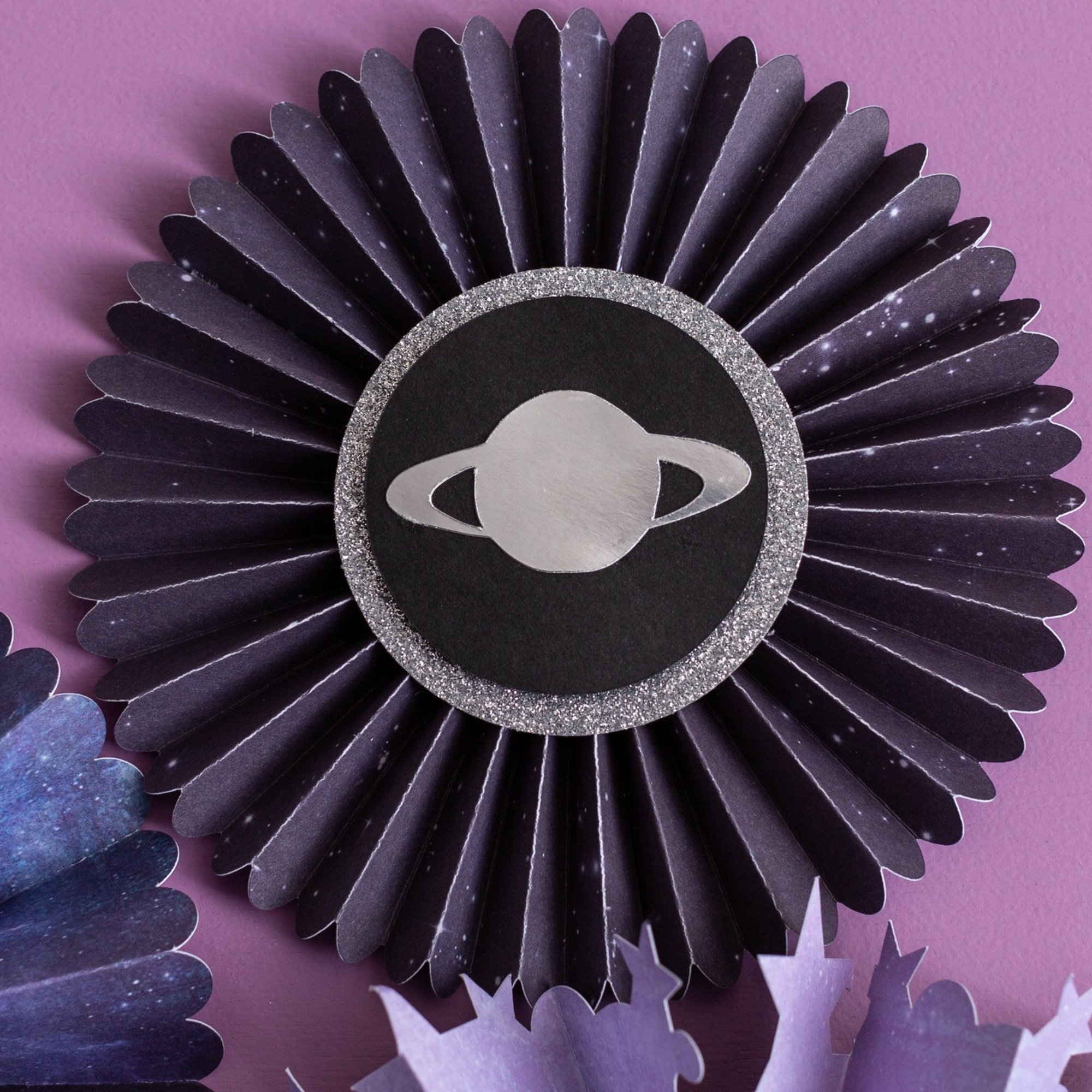 Un abanico de papel circular y plegado con un símbolo de Saturno.