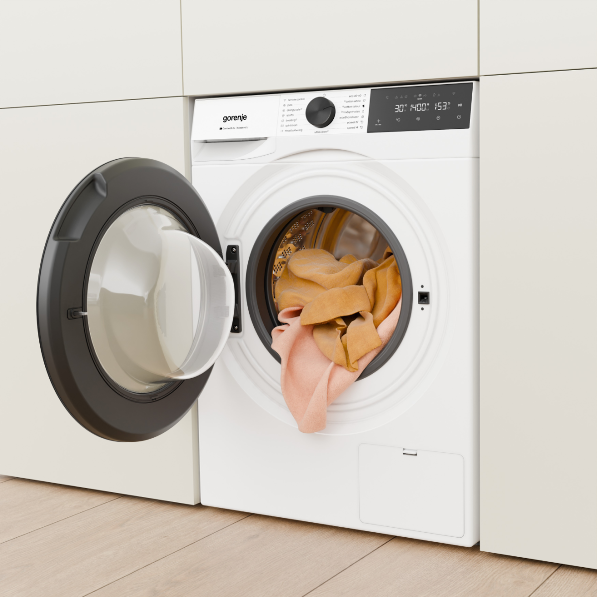 Egy fehér Gorenje mosógép nyitott ajtóval, barna ruhákkal.