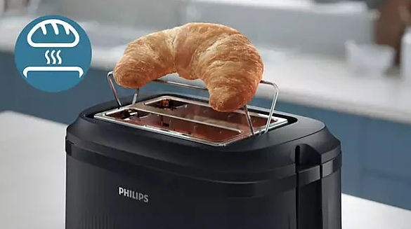 Złocisty rogalik podgrzewa się w czarnej tosterze Philips.