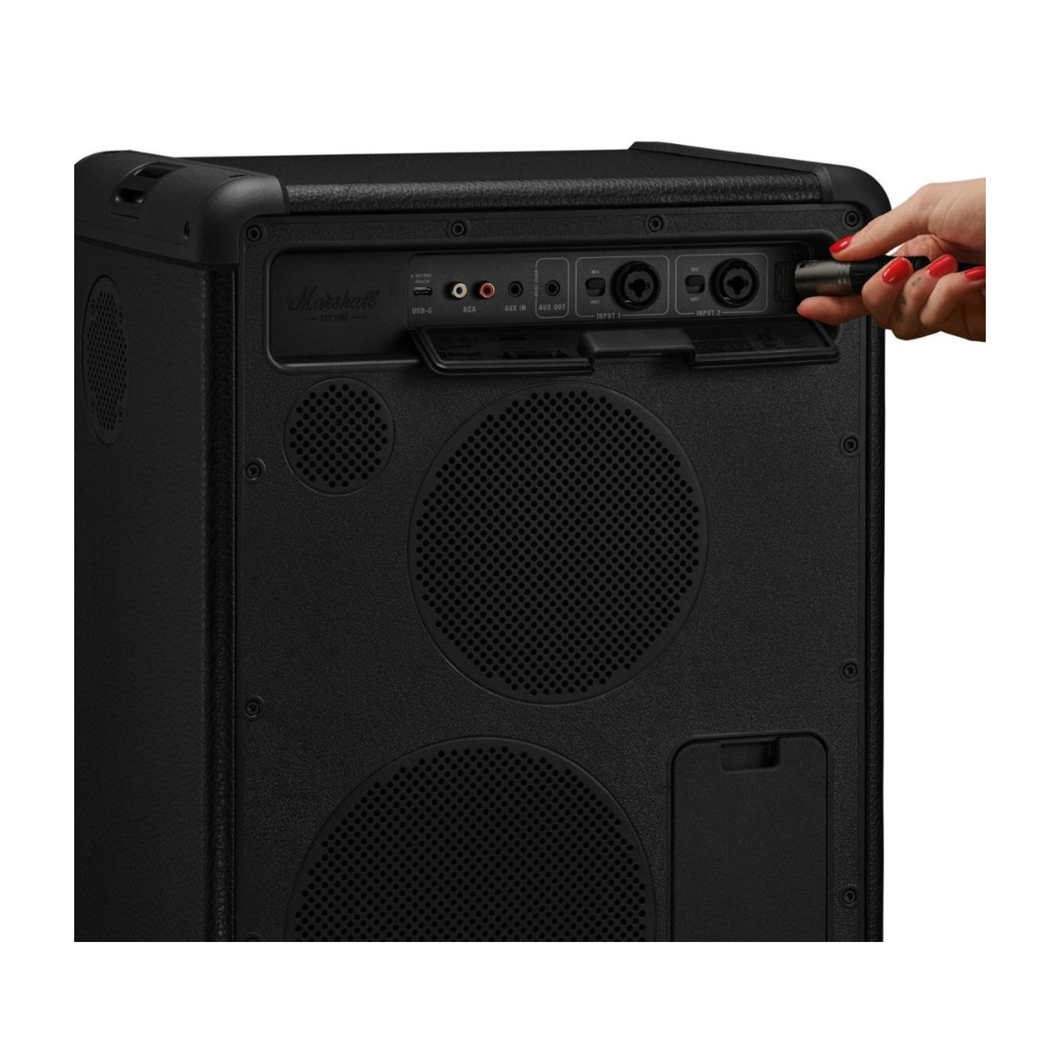 Una mano con unghie rosse inserisce un cavo nell'amplificatore Marshall.