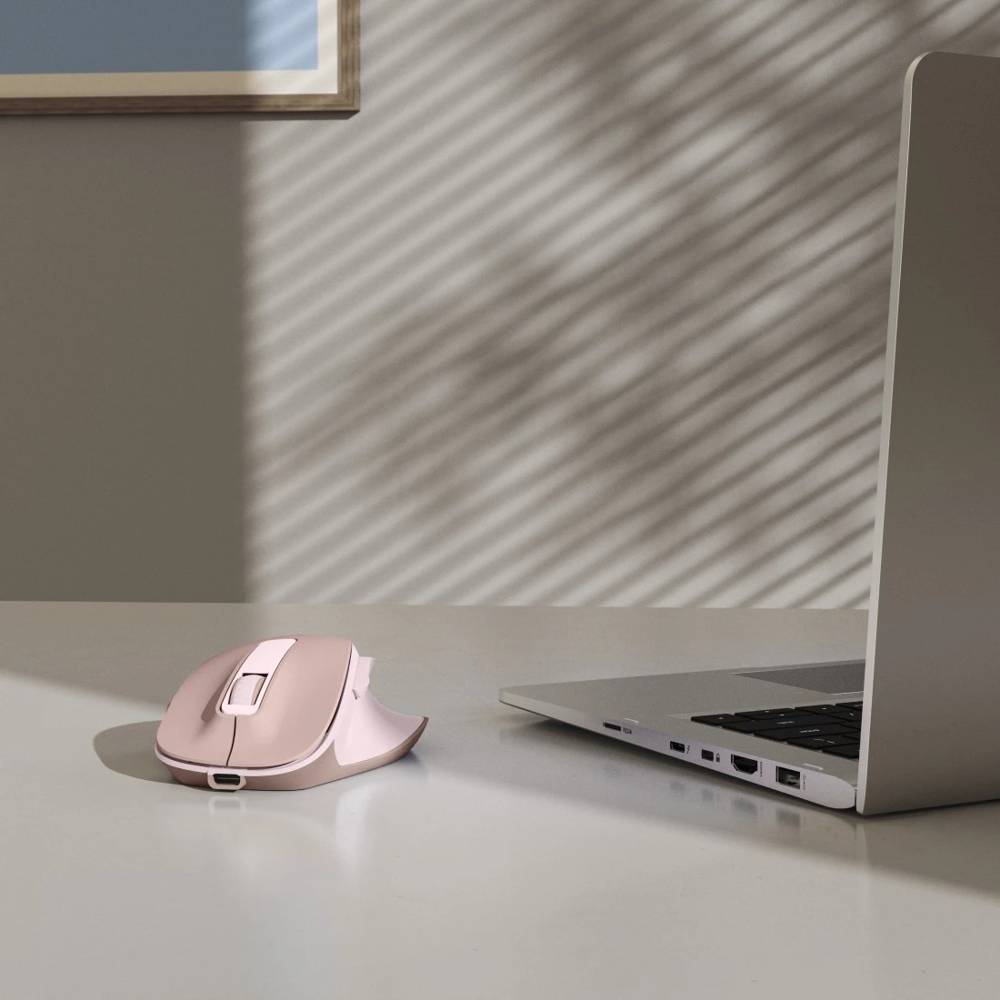 Różowa mysz komputerowa i laptop na biurku.