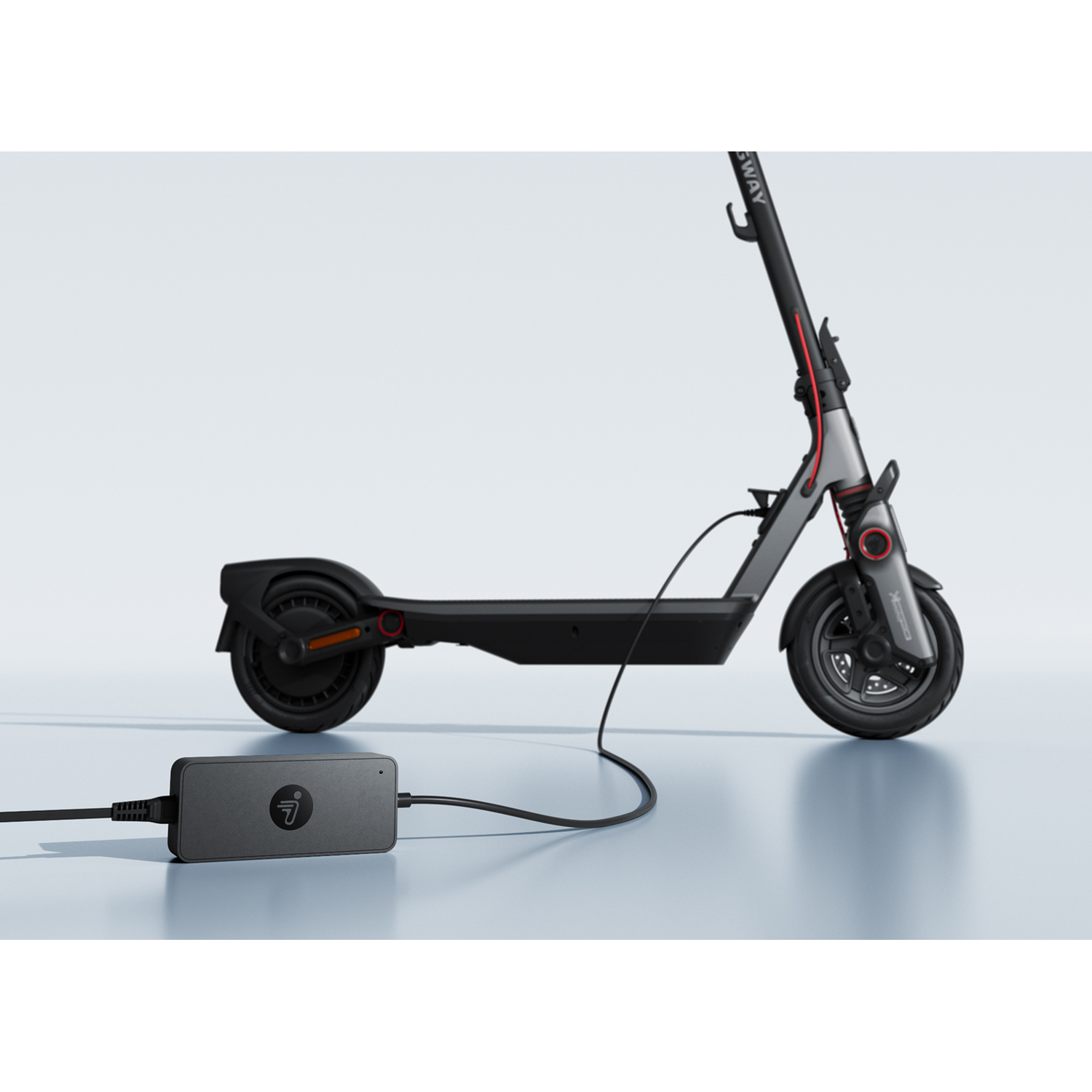 Een zwarte elektrische step wordt opgeladen via een adapter.