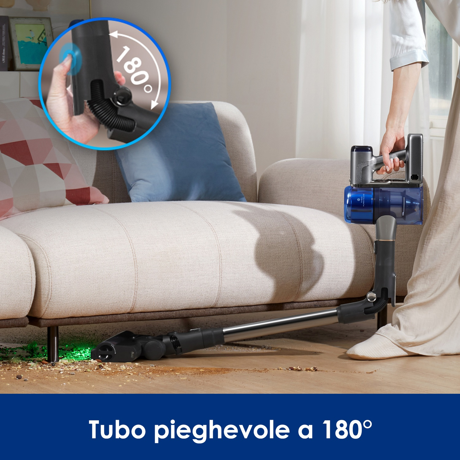 Un aspirapolvere portatile viene usato sotto un divano per pulire detriti, con tubo pieghevole 180°.