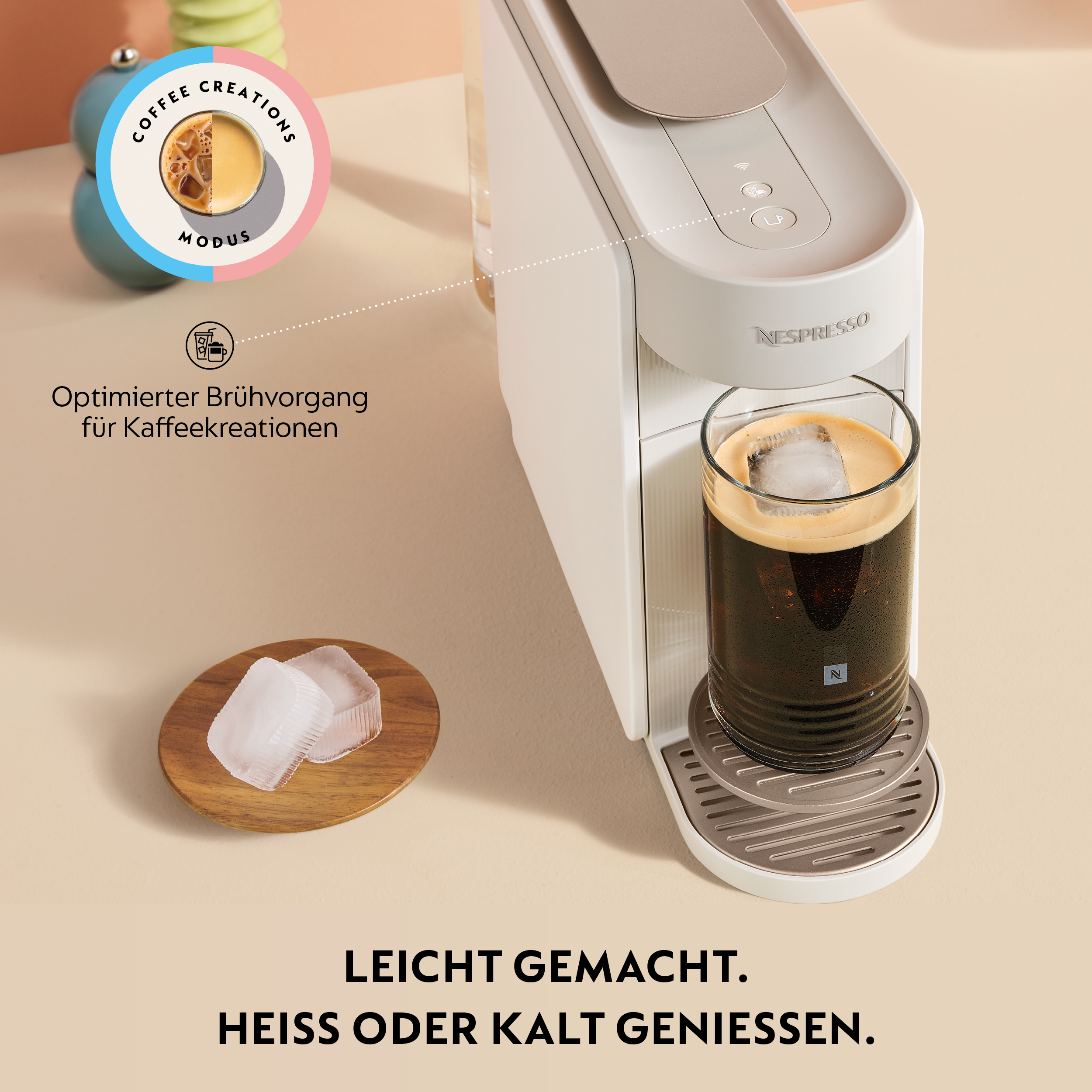Eine weiße Nespresso-Maschine mit einem Glas Eiskaffee und Eiswürfeln auf einem Holzbrett.