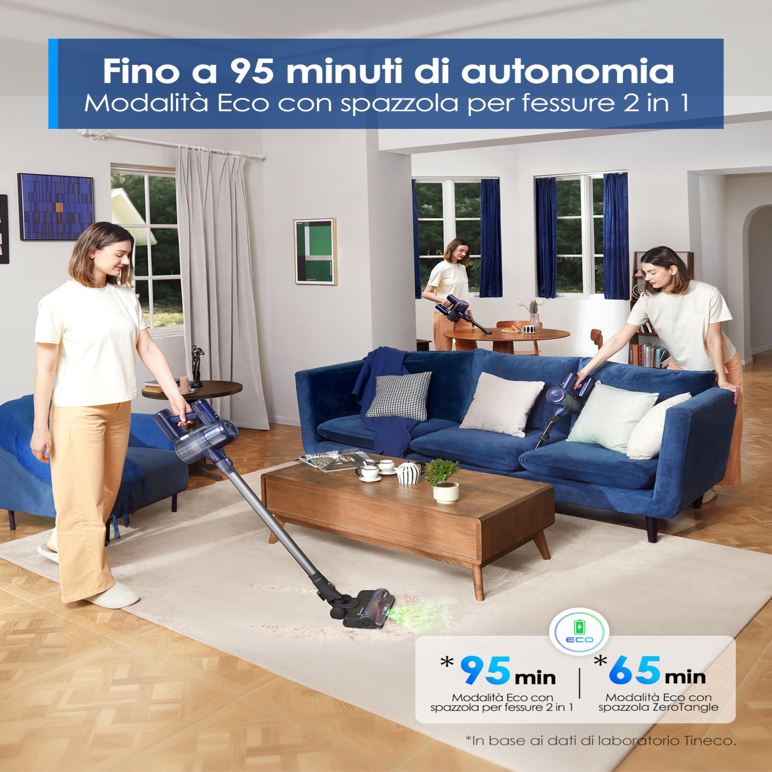 Due donne aspirano un salotto con un aspirapolvere senza fili. 'Fino a 95 min di autonomia'.