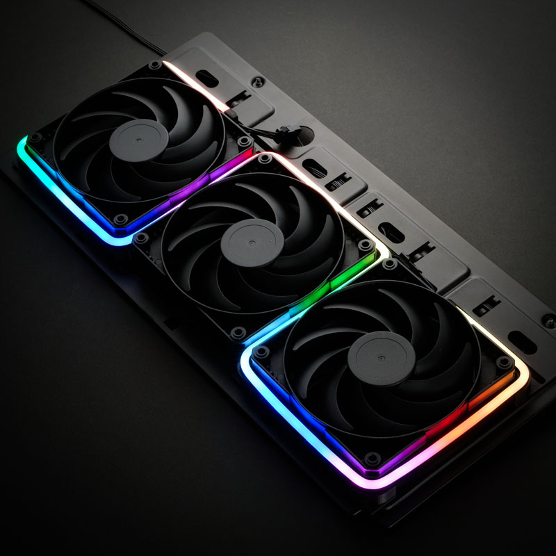 Drei schwarze Computerlüfter mit RGB-Beleuchtung auf dunkler Oberfläche.