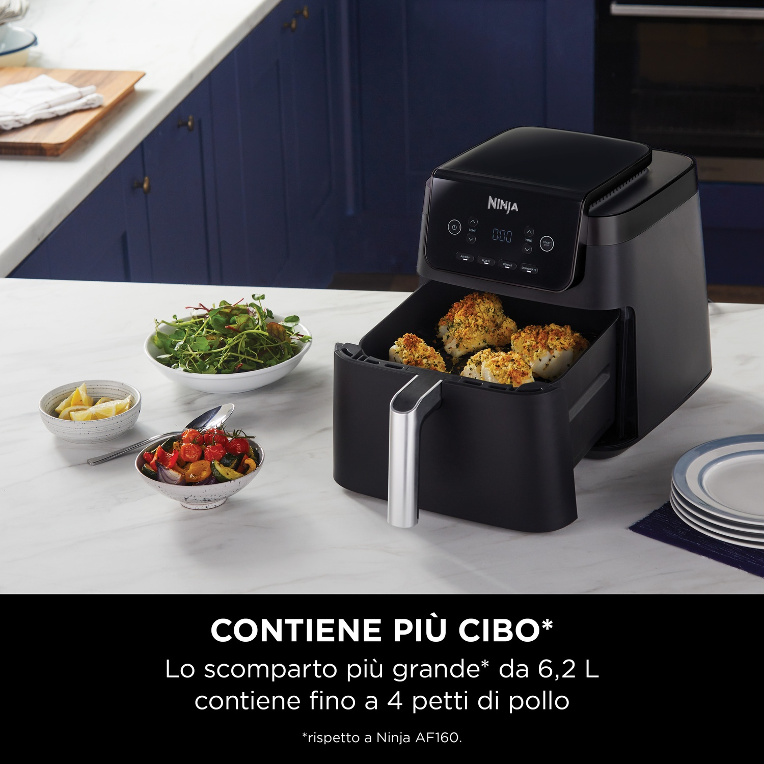 Una friggitrice ad aria Ninja nera con cibo cotto e ciotole di contorni.